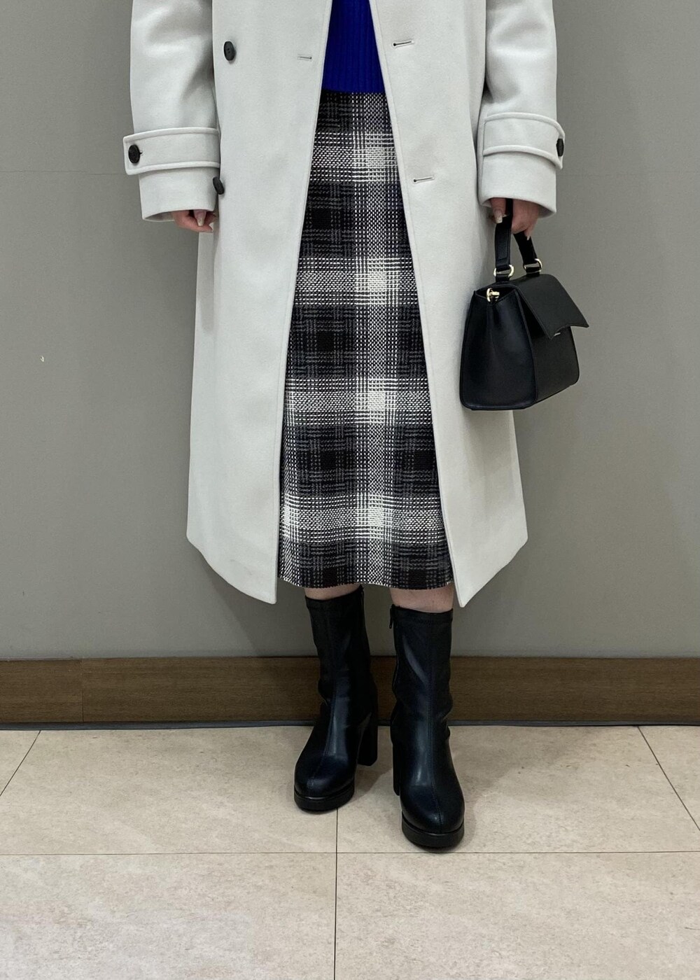 ブルー系のニット/セーター、ブラック系のショルダーバッグ、ブラック系のブーツを着用したレディースの秋コーディネートの4枚目の写真