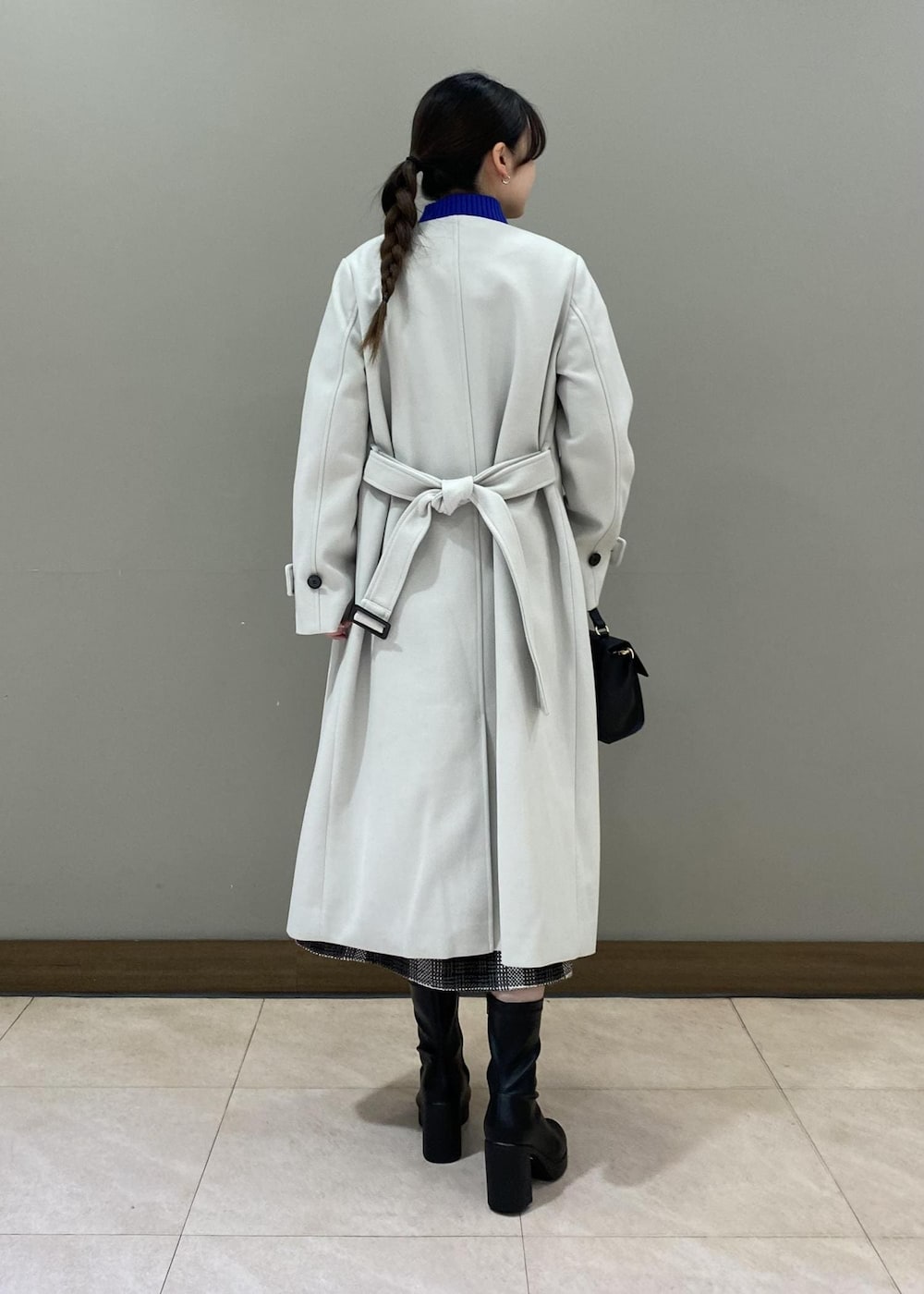 ブルー系のニット/セーター、ブラック系のショルダーバッグ、ブラック系のブーツを着用したレディースの秋コーディネートの2枚目の写真