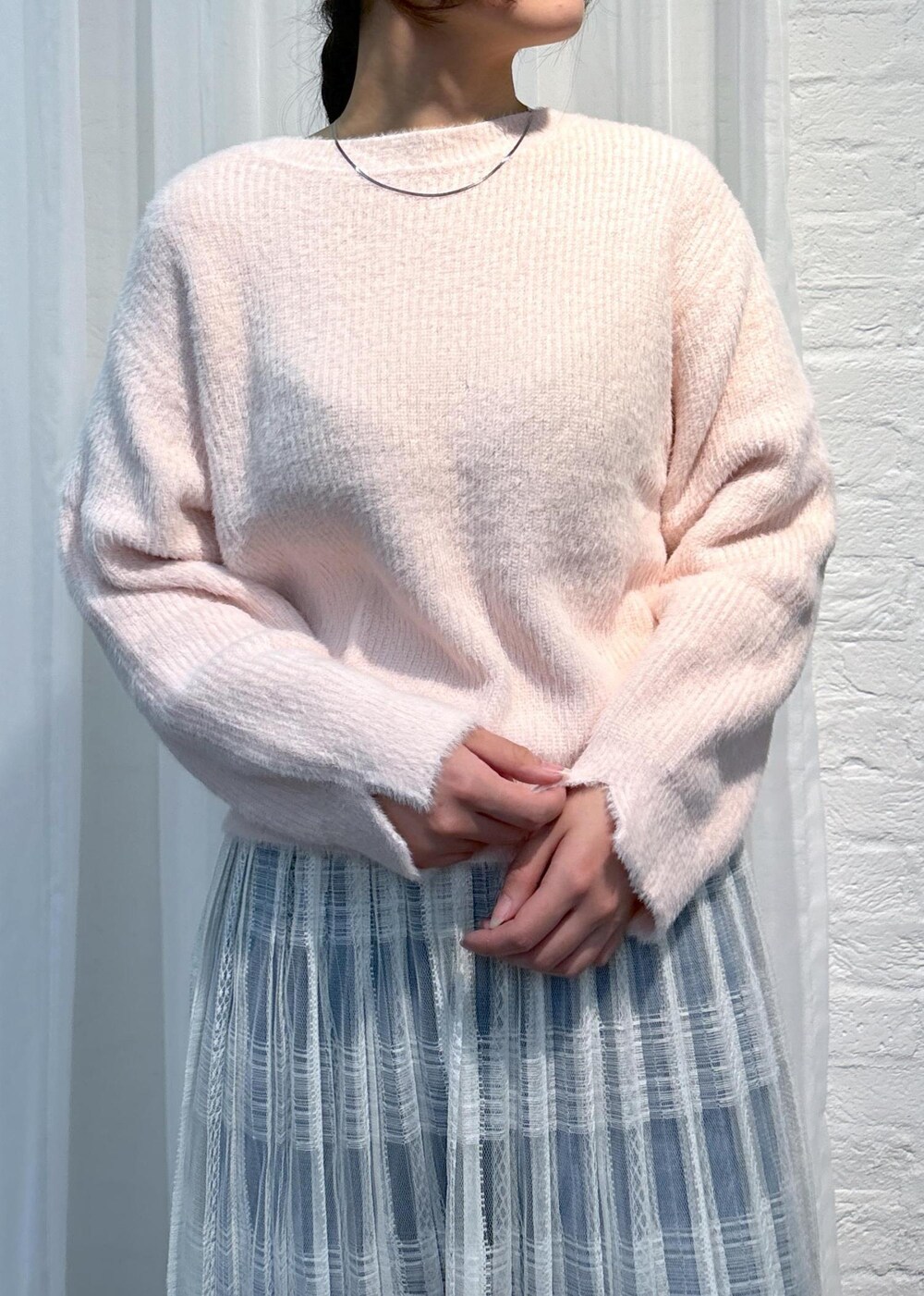 ブルー系のデニムパンツ、ピンク系のニット/セーター、ホワイト系のスカートを着用したレディースの冬コーディネートの5枚目の写真