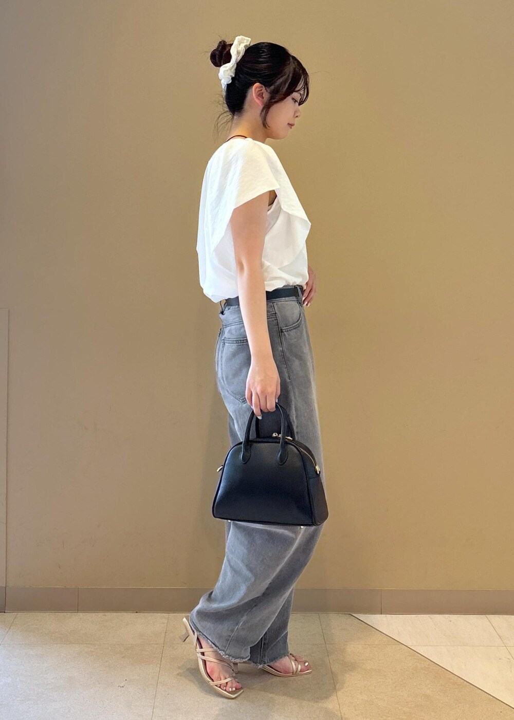 ホワイト系のシャツ/ブラウス、ゴールド系のサンダル、グレー系のデニムパンツを着用したレディースの夏コーディネートの2枚目の写真