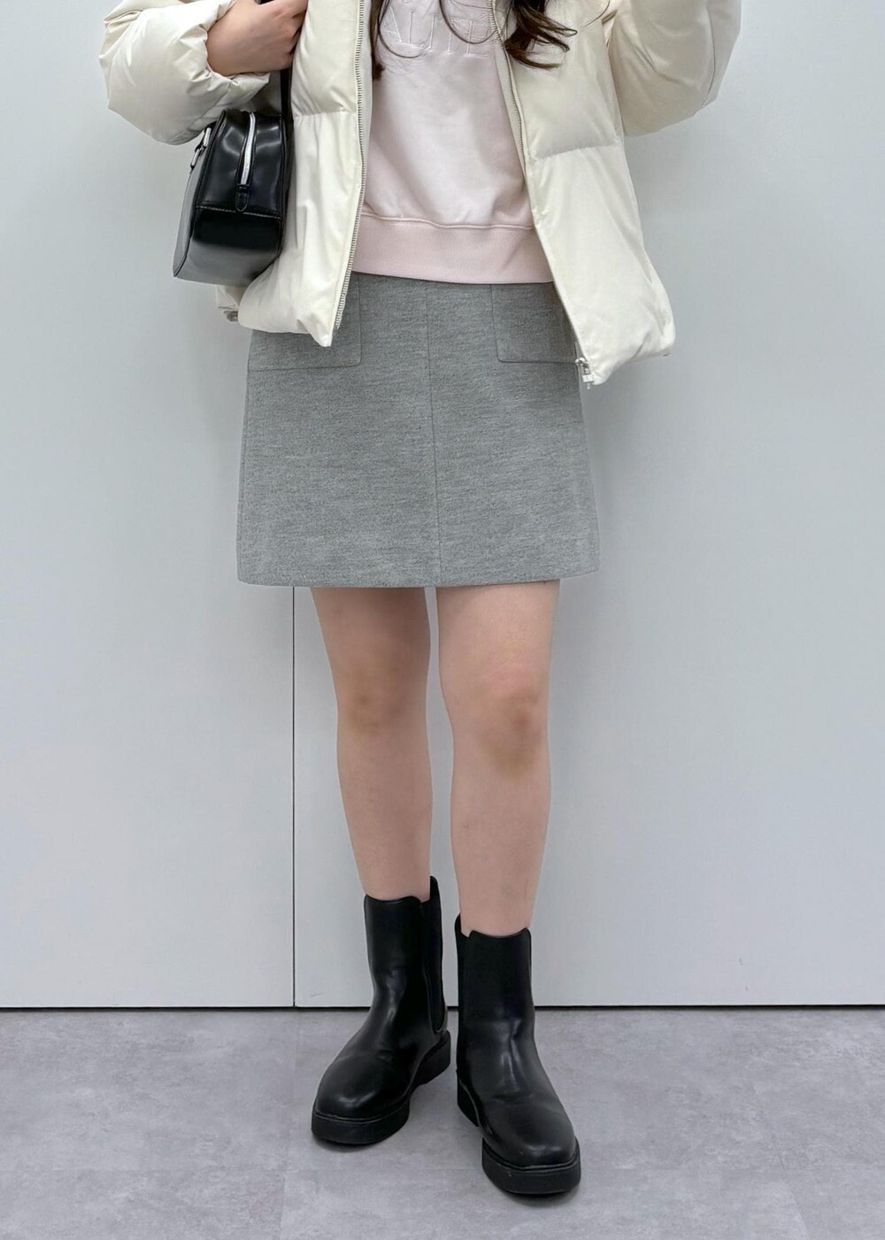 ブラック系のブーツ、ベージュ系のダウンジャケット/コート、ブラック系のボストンバッグを着用したレディースの秋コーディネートの7枚目の写真