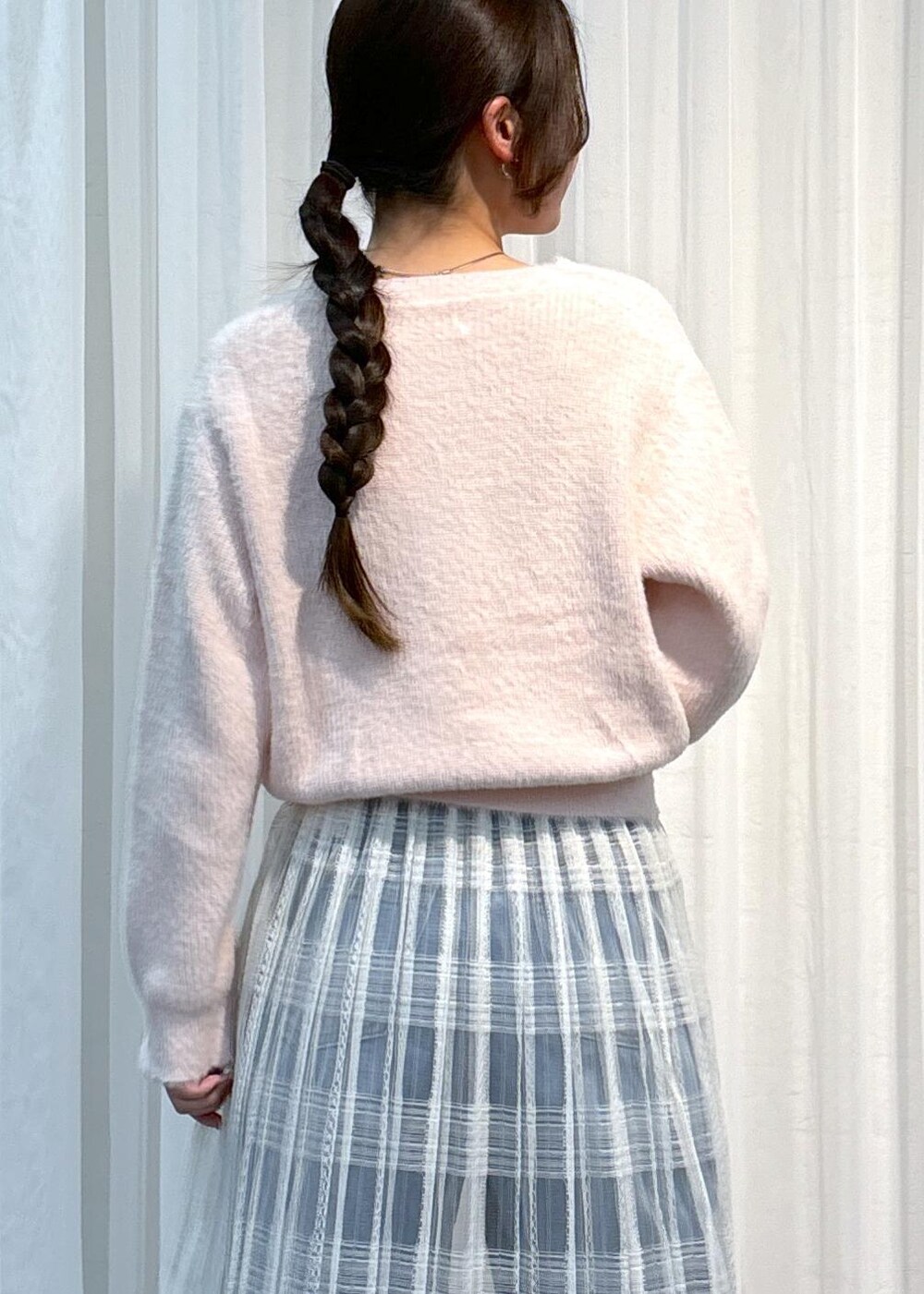 ブルー系のデニムパンツ、ピンク系のニット/セーター、ホワイト系のスカートを着用したレディースの冬コーディネートの6枚目の写真