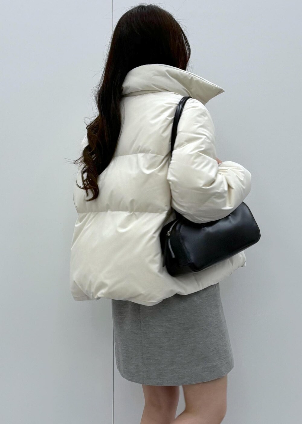 ブラック系のブーツ、ベージュ系のダウンジャケット/コート、ブラック系のボストンバッグを着用したレディースの秋コーディネートの6枚目の写真