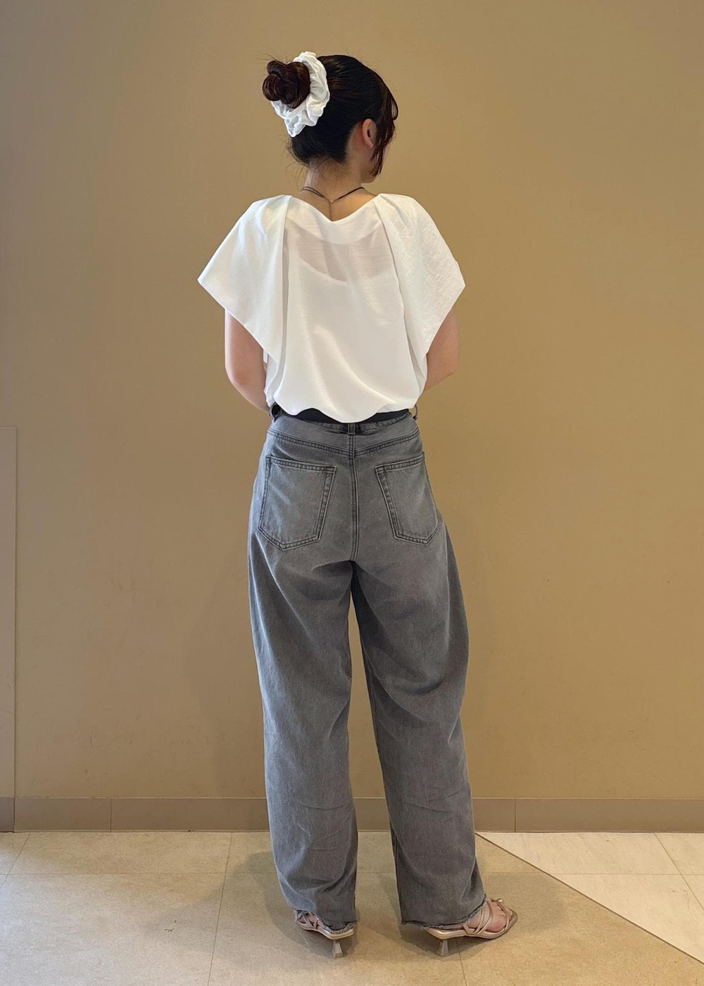 ホワイト系のシャツ/ブラウス、ゴールド系のサンダル、グレー系のデニムパンツを着用したレディースの夏コーディネートの3枚目の写真