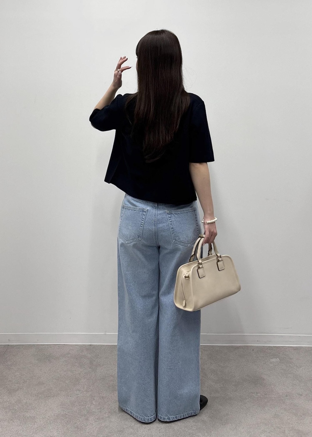 ホワイト系のボストンバッグ、ブルー系のデニムパンツ、ブルー系のカーディガン/ボレロを着用したレディースの春コーディネートの3枚目の写真