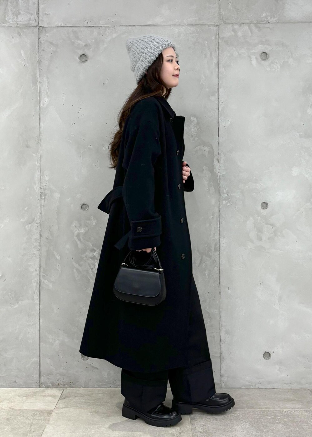 グレー系のニット/セーター、ブラック系のその他アウター、ブラック系のハンドバッグを着用したレディースの冬コーディネートの2枚目の写真