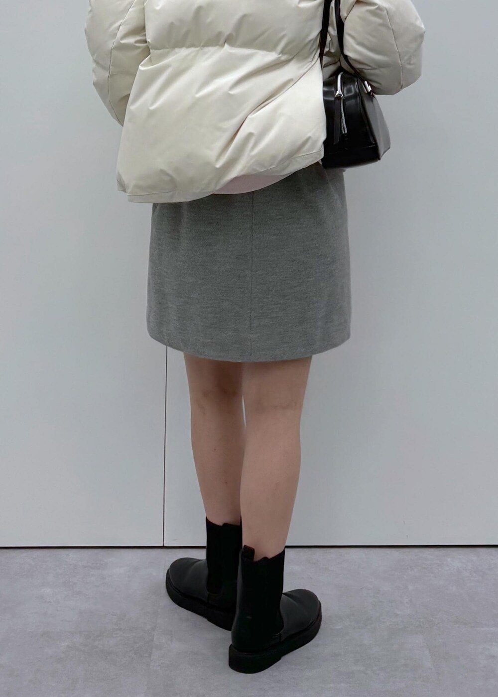 ブラック系のブーツ、ベージュ系のダウンジャケット/コート、ブラック系のボストンバッグを着用したレディースの秋コーディネートの9枚目の写真