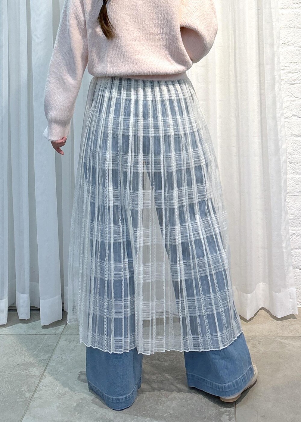 ブルー系のデニムパンツ、ピンク系のニット/セーター、ホワイト系のスカートを着用したレディースの冬コーディネートの8枚目の写真