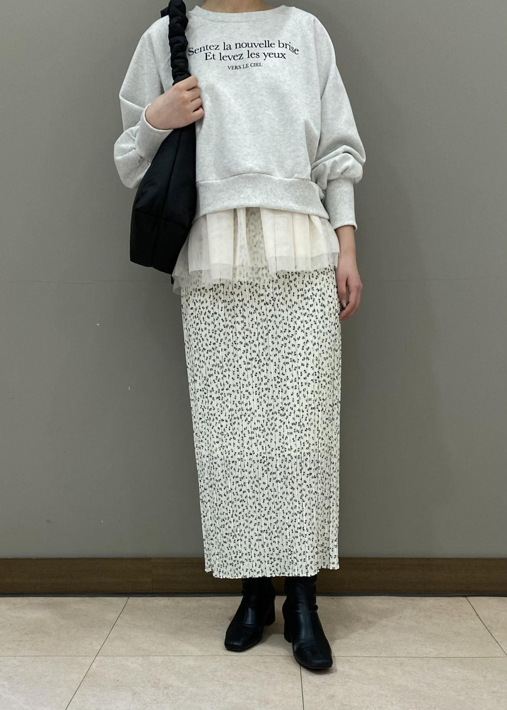 ホワイト系のスカート、ブラック系のショルダーバッグ、ホワイト系のベストを着用したレディースの冬コーディネートの4枚目の写真