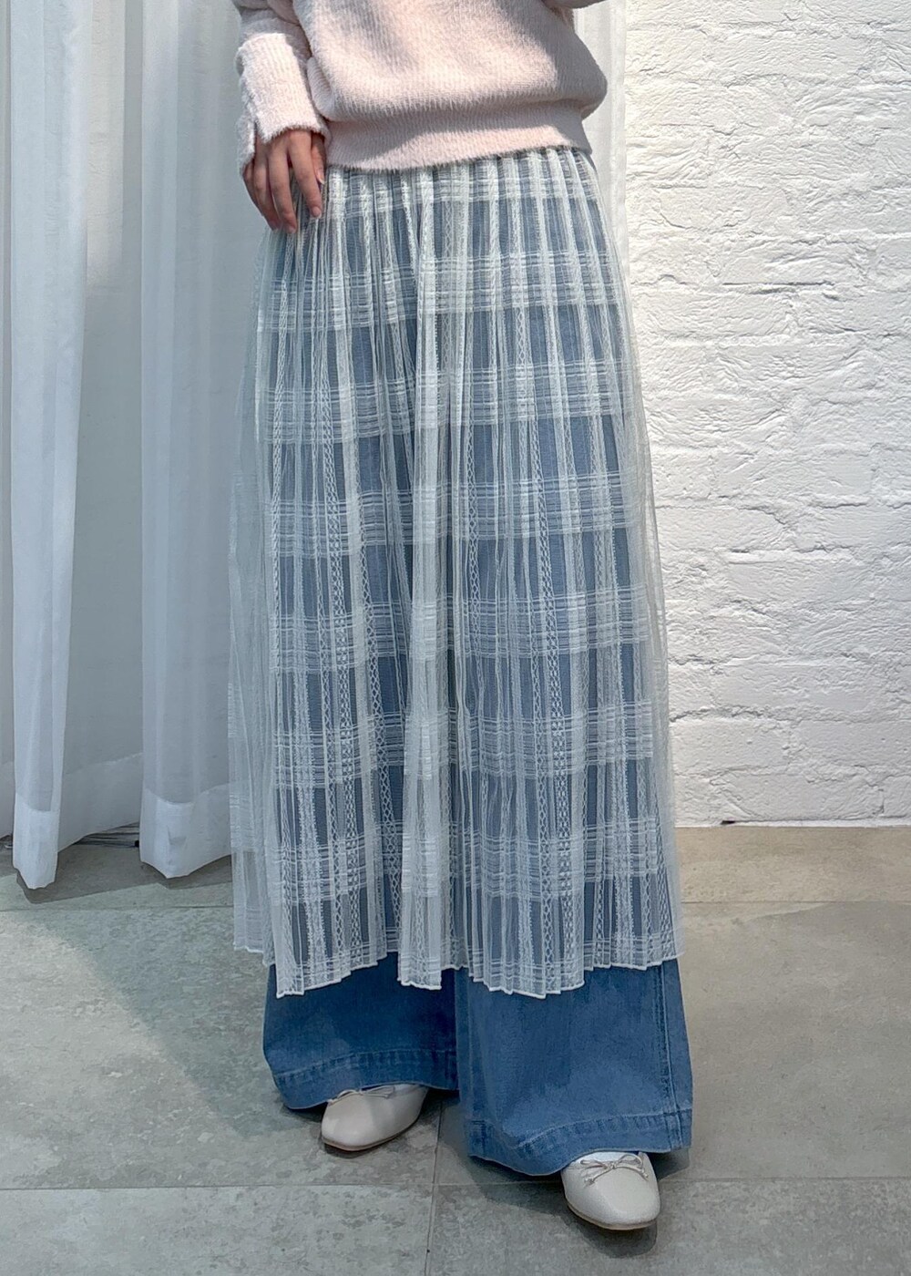 ブルー系のデニムパンツ、ピンク系のニット/セーター、ホワイト系のスカートを着用したレディースの冬コーディネートの7枚目の写真