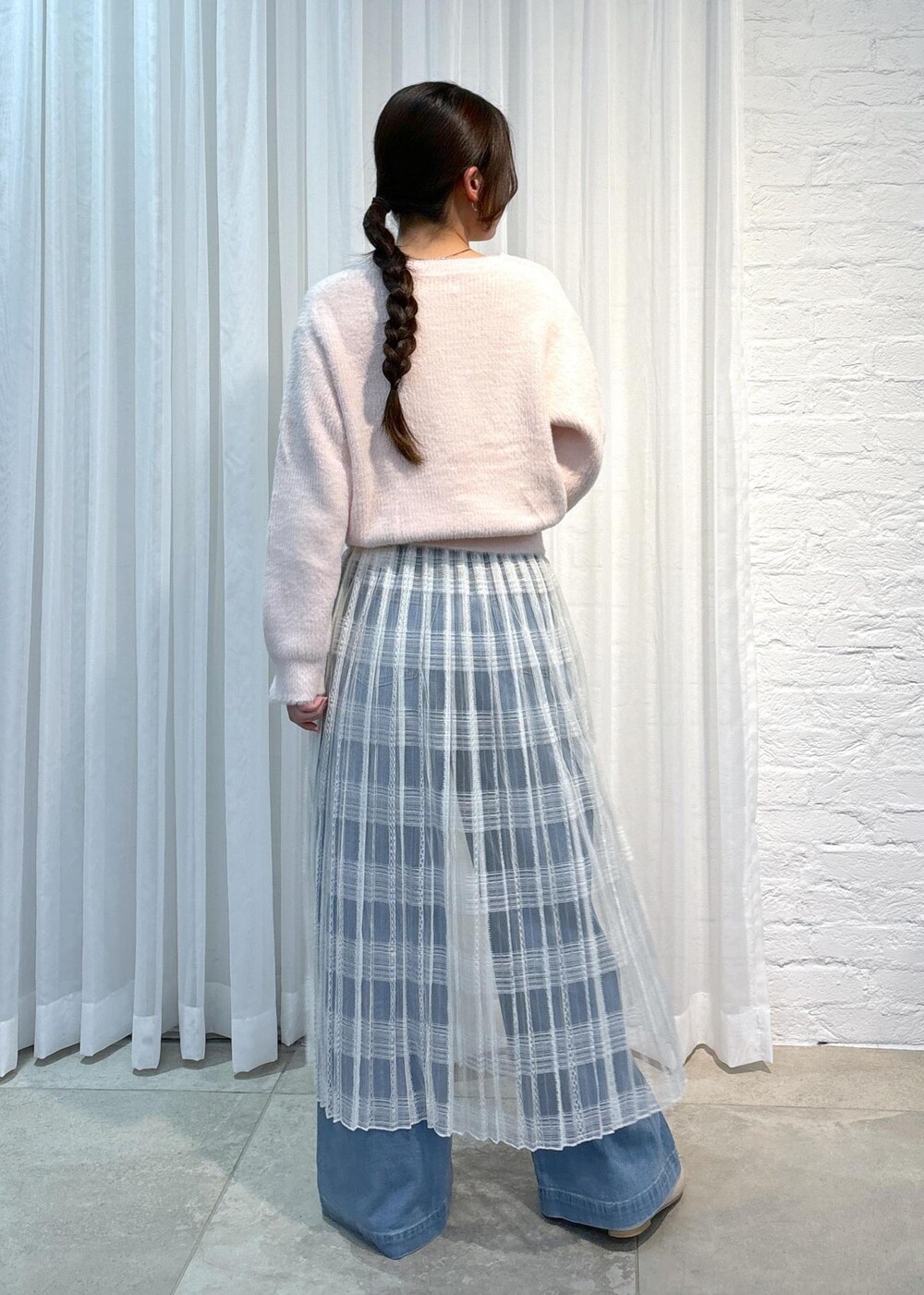 ブルー系のデニムパンツ、ピンク系のニット/セーター、ホワイト系のスカートを着用したレディースの冬コーディネートの3枚目の写真