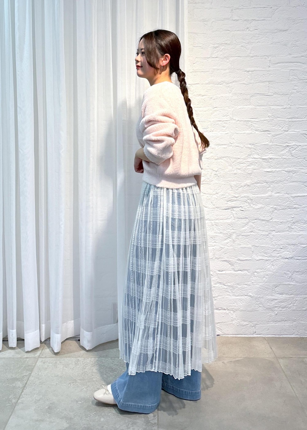 ブルー系のデニムパンツ、ピンク系のニット/セーター、ホワイト系のスカートを着用したレディースの冬コーディネートの4枚目の写真