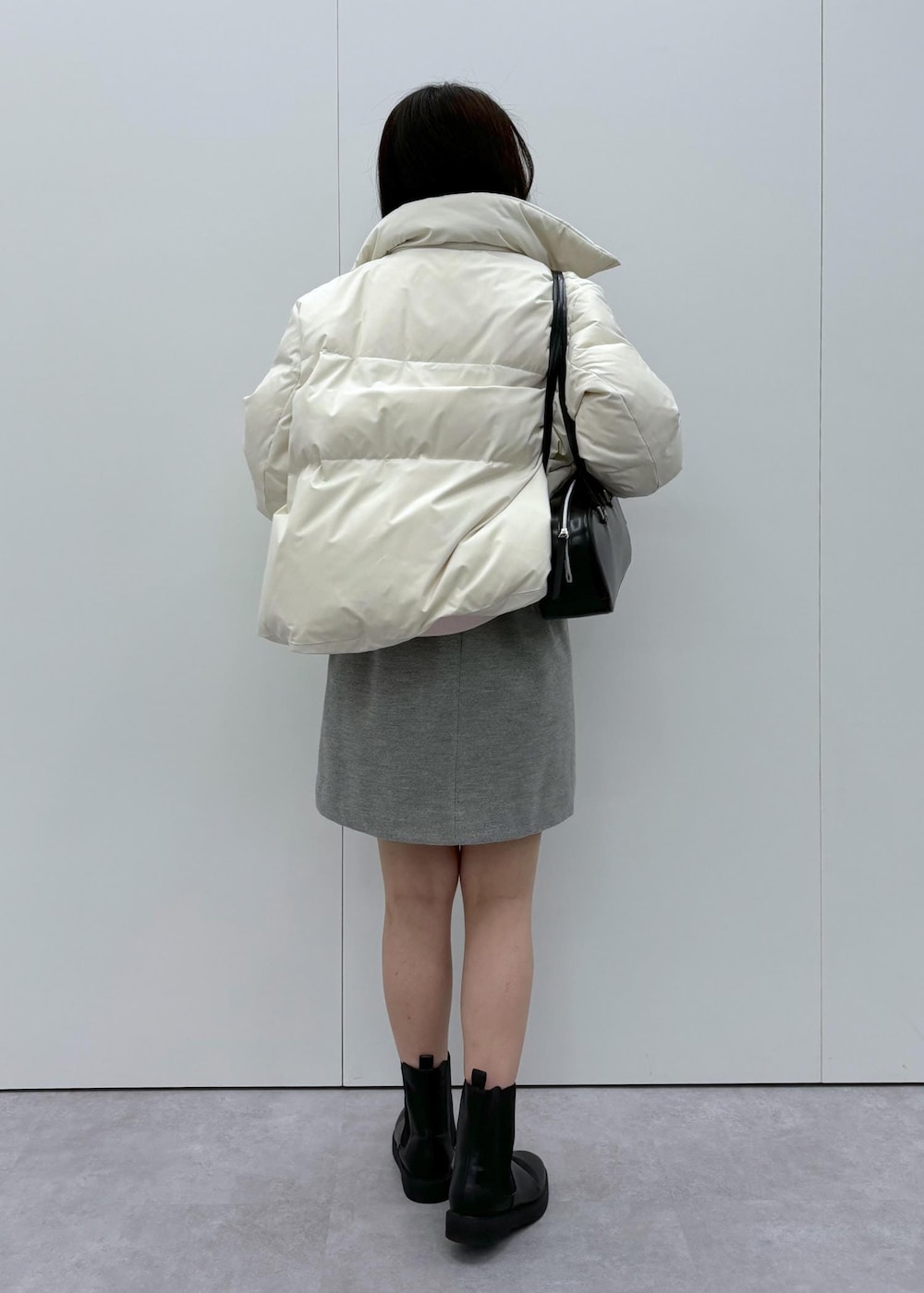 ブラック系のブーツ、ベージュ系のダウンジャケット/コート、ブラック系のボストンバッグを着用したレディースの秋コーディネートの3枚目の写真