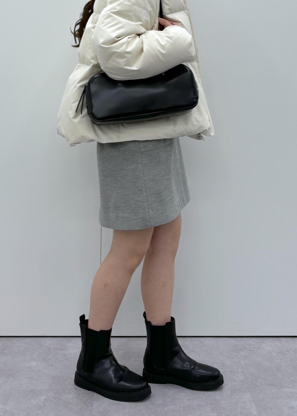 ブラック系のブーツ、ベージュ系のダウンジャケット/コート、ブラック系のボストンバッグを着用したレディースの秋コーディネートの8枚目の写真