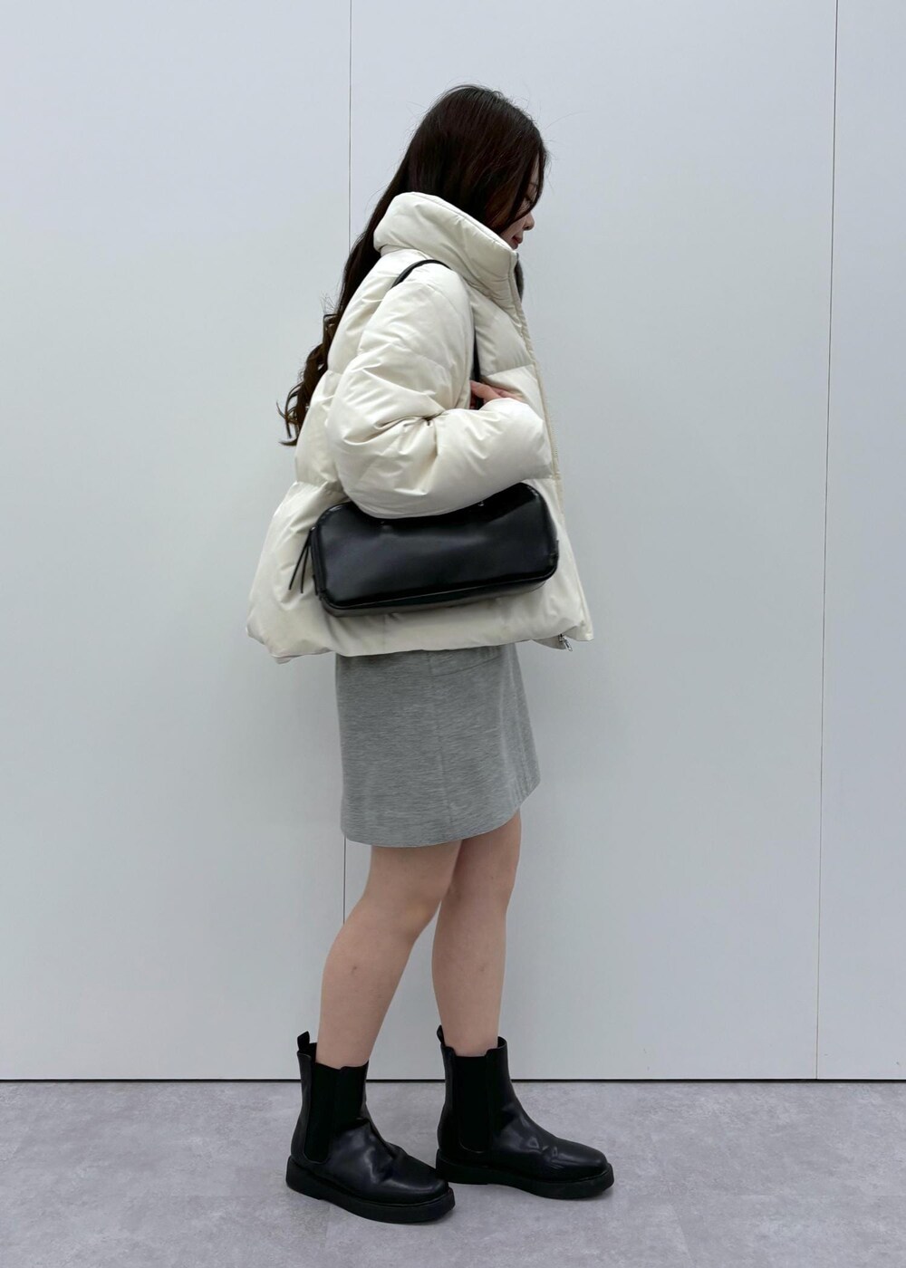 ブラック系のブーツ、ベージュ系のダウンジャケット/コート、ブラック系のボストンバッグを着用したレディースの秋コーディネートの2枚目の写真