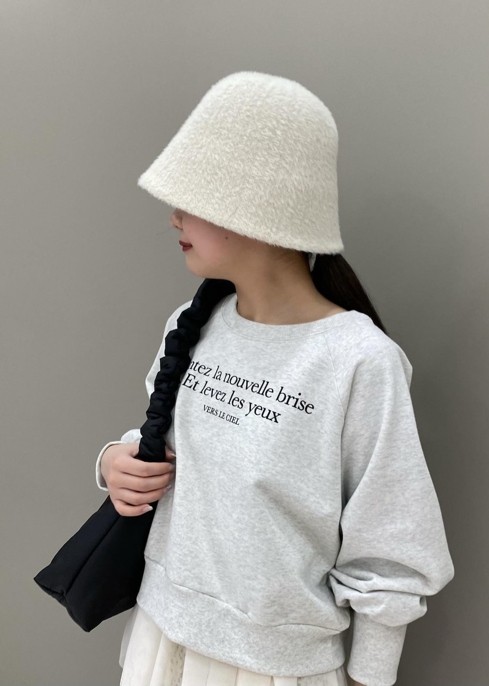 ホワイト系のスカート、ブラック系のショルダーバッグ、ホワイト系のベストを着用したレディースの冬コーディネートの3枚目の写真