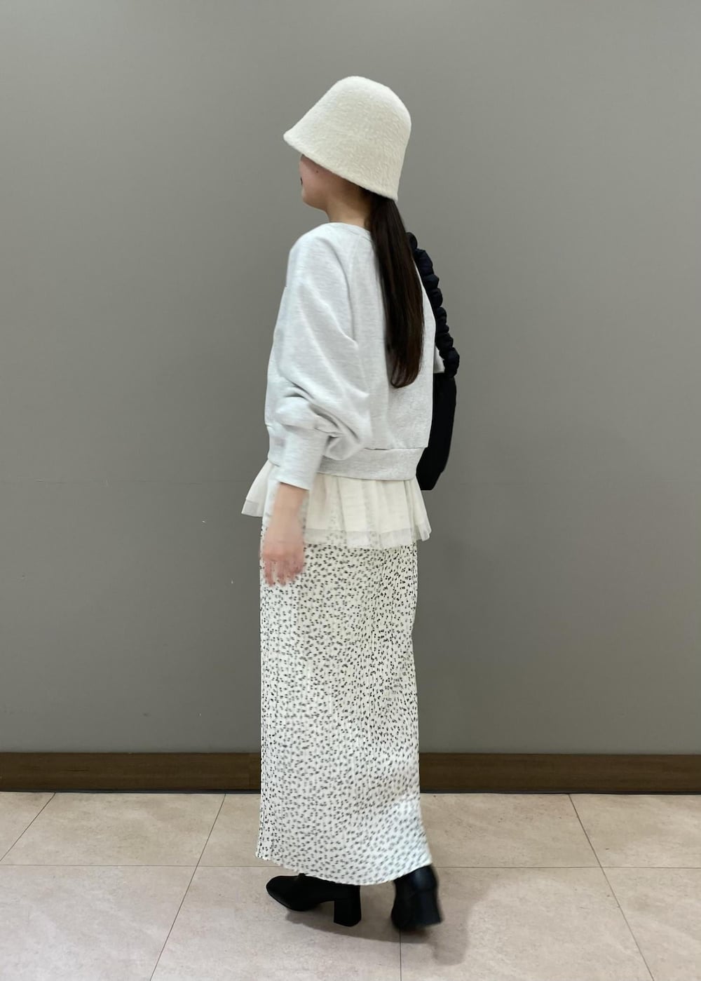 ホワイト系のスカート、ブラック系のショルダーバッグ、ホワイト系のベストを着用したレディースの冬コーディネートの2枚目の写真