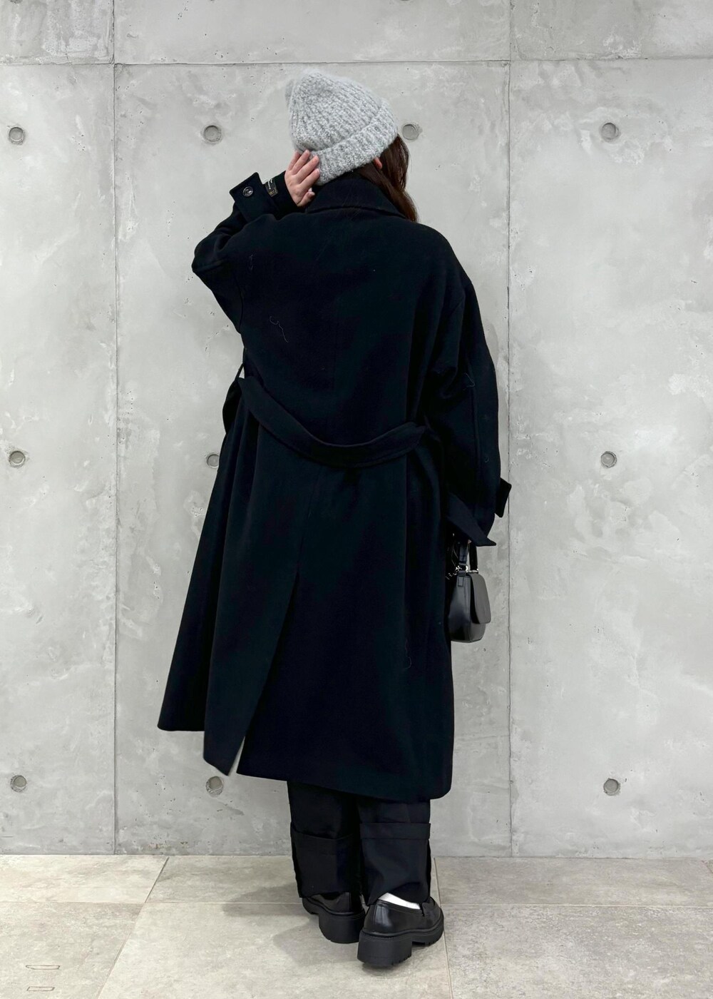 グレー系のニット/セーター、ブラック系のその他アウター、ブラック系のハンドバッグを着用したレディースの冬コーディネートの3枚目の写真