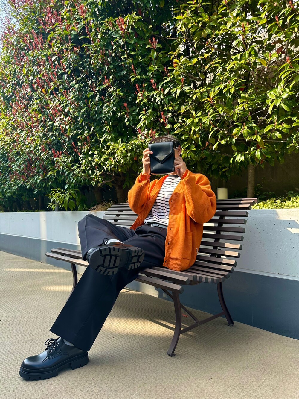 ブラック系のスラックス、ホワイト系のTシャツ/カットソー、オレンジ系のカーディガン/ボレロを着用したメンズの春コーディネートの2枚目の写真