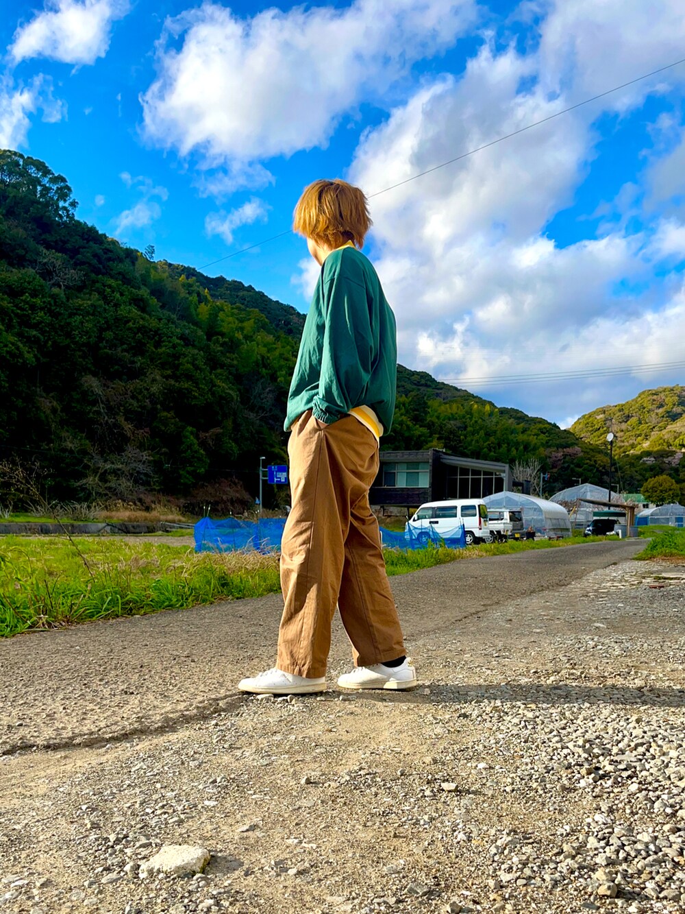 グリーン系のTシャツ/カットソー、ブラウン系のスラックス、ホワイト系のスニーカーを着用したメンズの春コーディネートの2枚目の写真