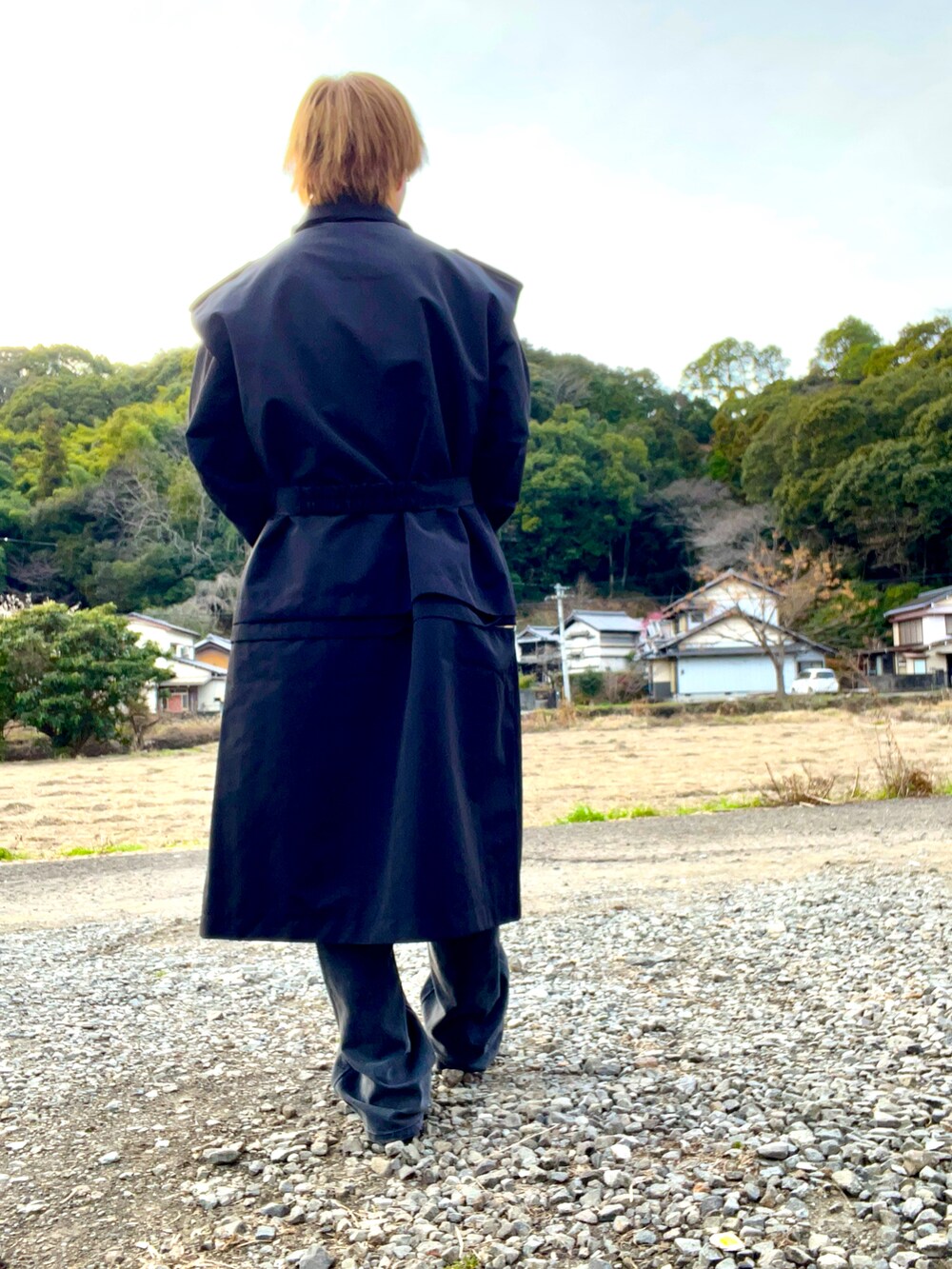 ブラック系のトレンチコート、グレー系のデニムパンツ、ブラック系のブーツを着用したメンズの冬コーディネートの3枚目の写真