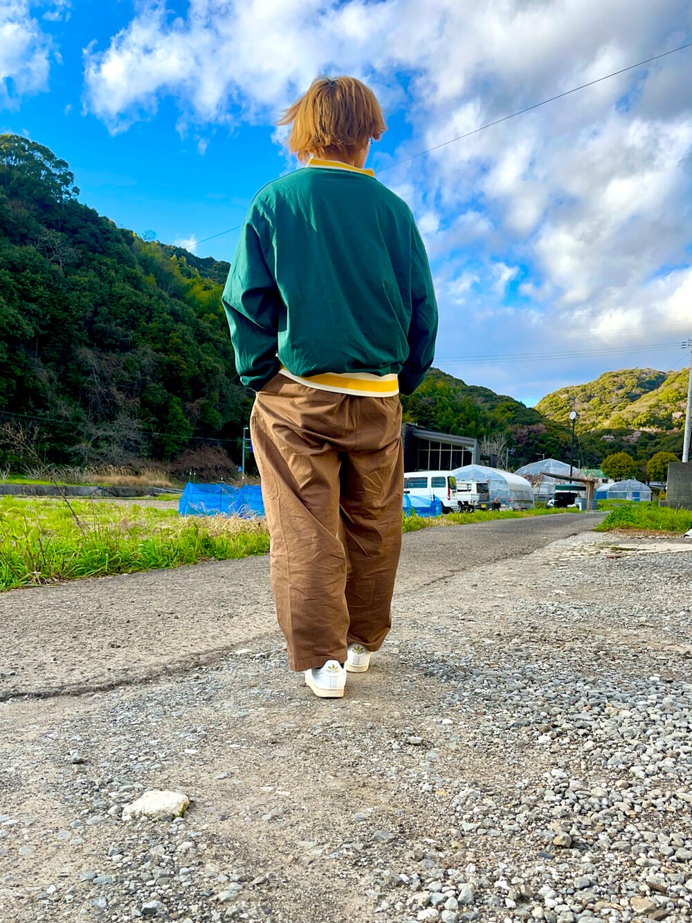 グリーン系のTシャツ/カットソー、ブラウン系のスラックス、ホワイト系のスニーカーを着用したメンズの春コーディネートの3枚目の写真