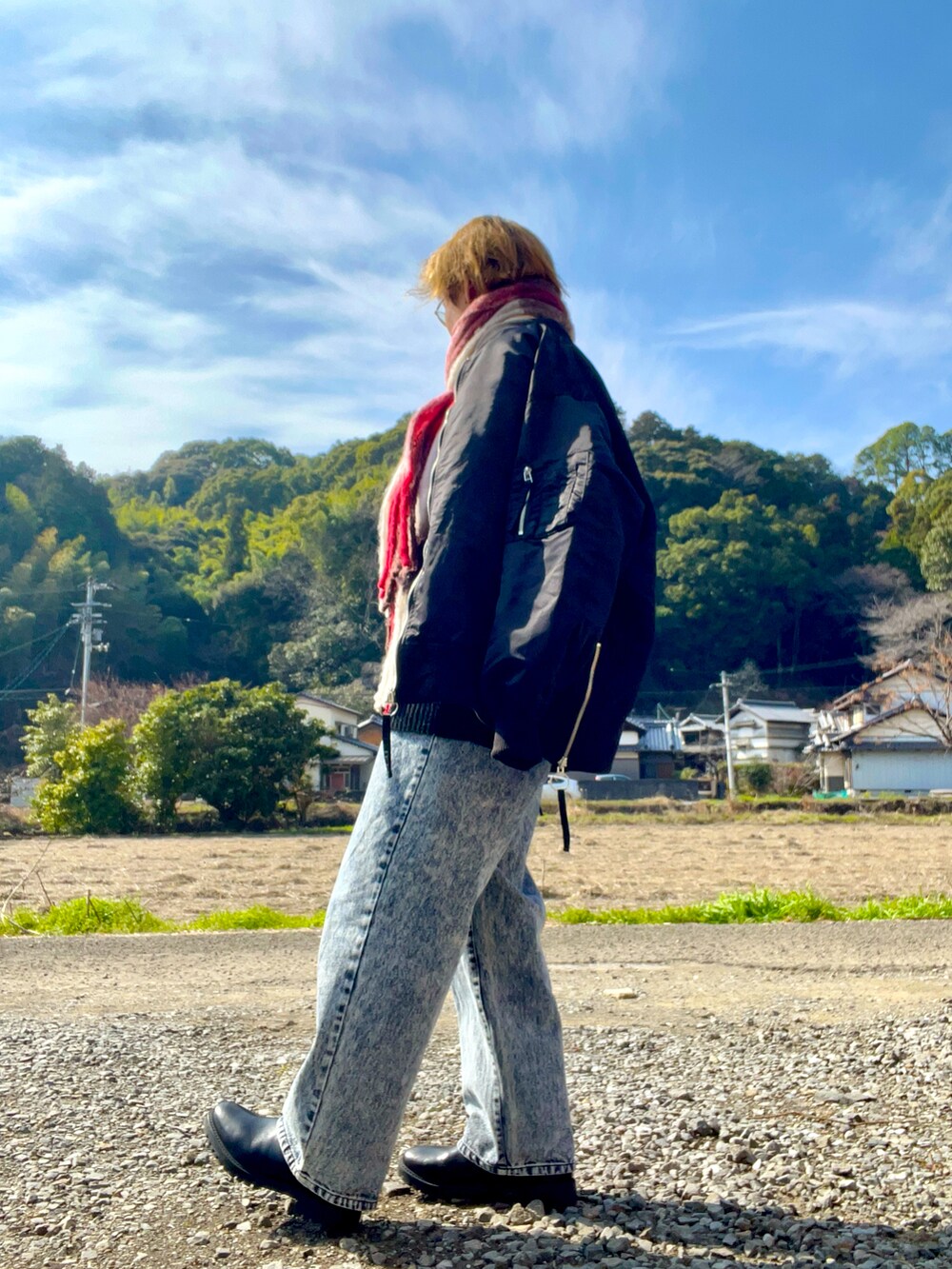 レッド系のニット/セーター、ブラック系のMA-1、ブルー系のデニムパンツを着用したメンズの春コーディネートの3枚目の写真