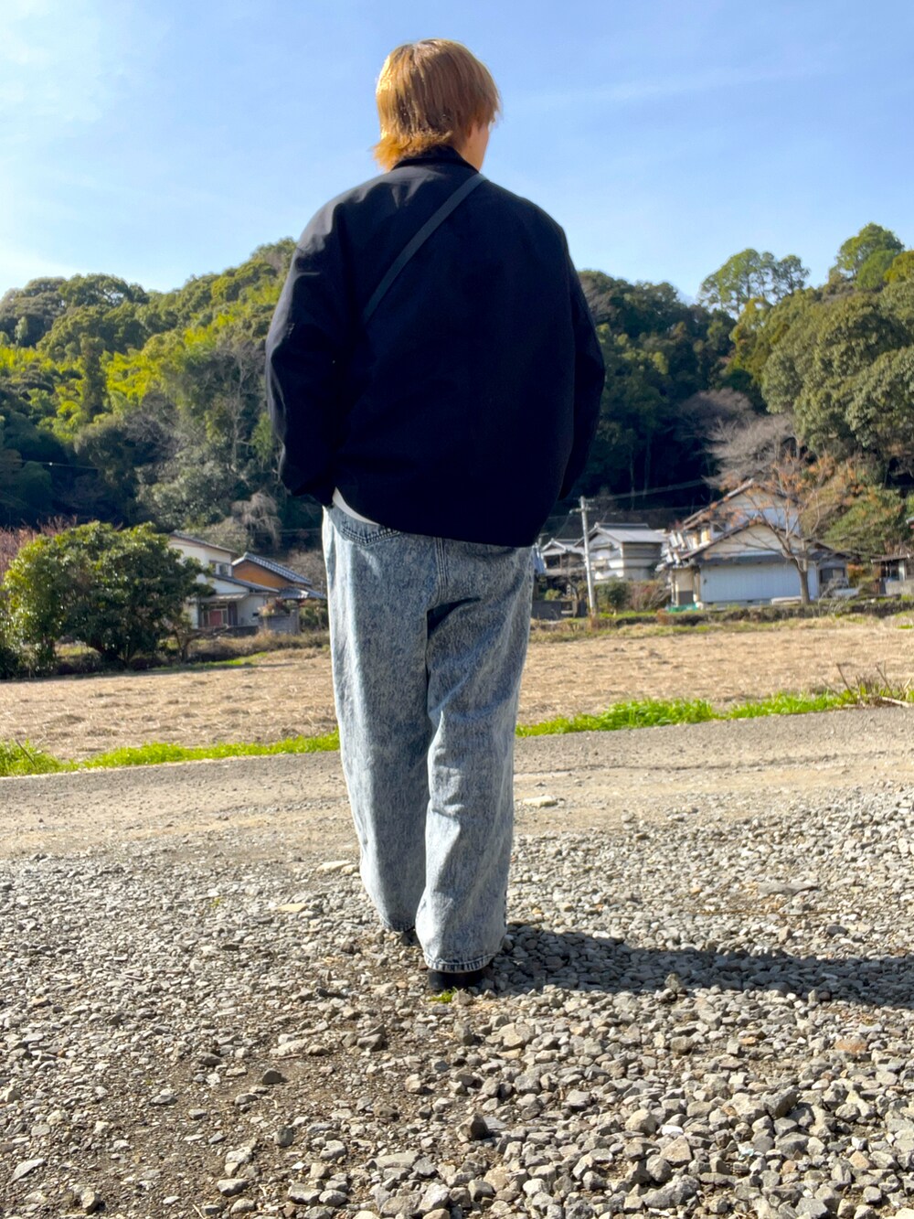 ブラック系のブルゾン、ホワイト系のスウェット、ブルー系のデニムパンツを着用したメンズの冬コーディネートの5枚目の写真