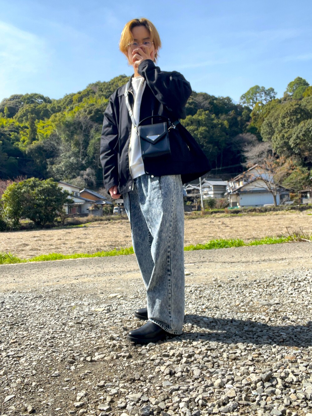 ブラック系のブルゾン、ホワイト系のスウェット、ブルー系のデニムパンツを着用したメンズの冬コーディネートの2枚目の写真