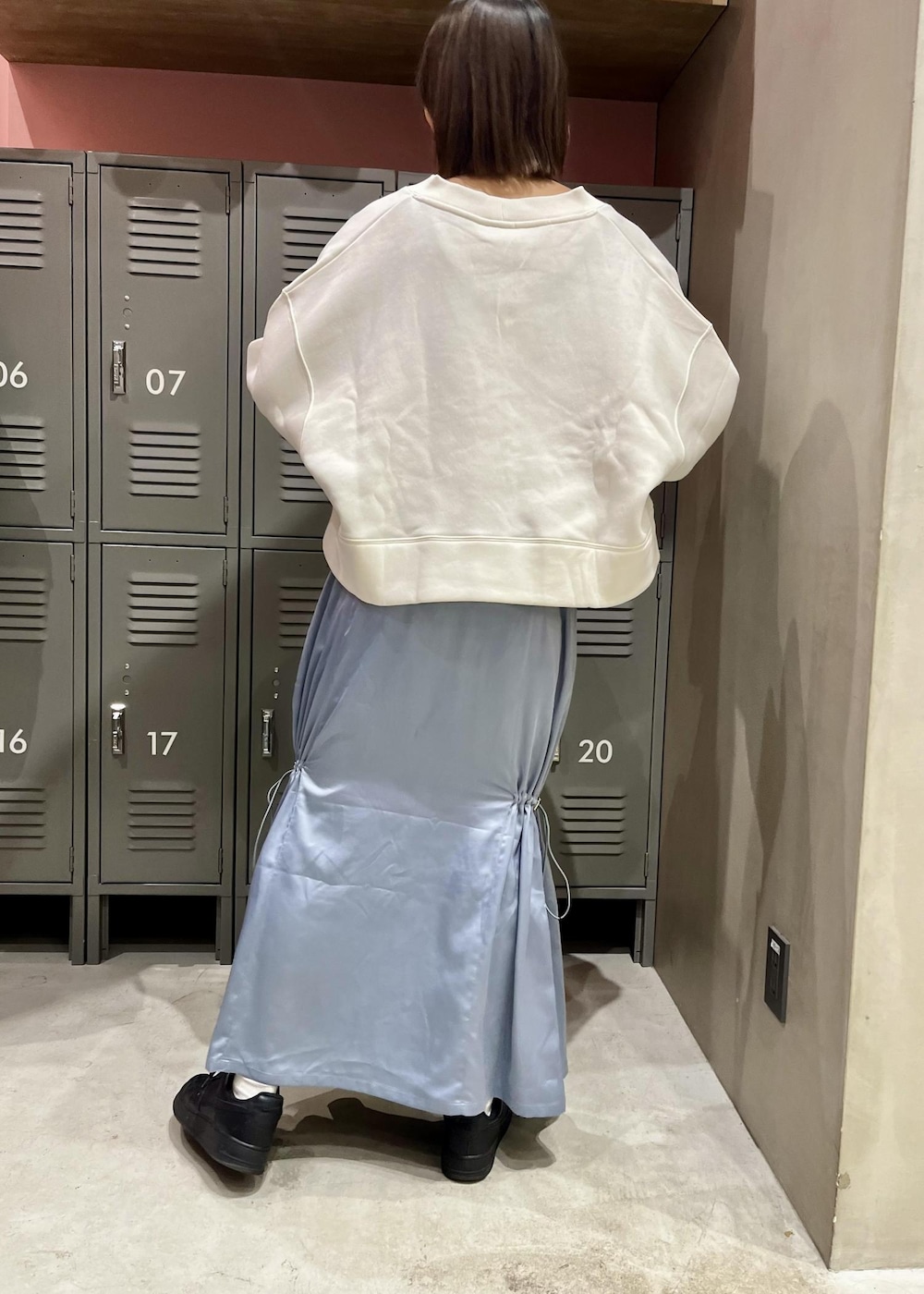 ブラック系のスニーカー、ホワイト系のカーディガン/ボレロ、シルバー系のワンピースを着用したレディースの冬コーディネートの2枚目の写真