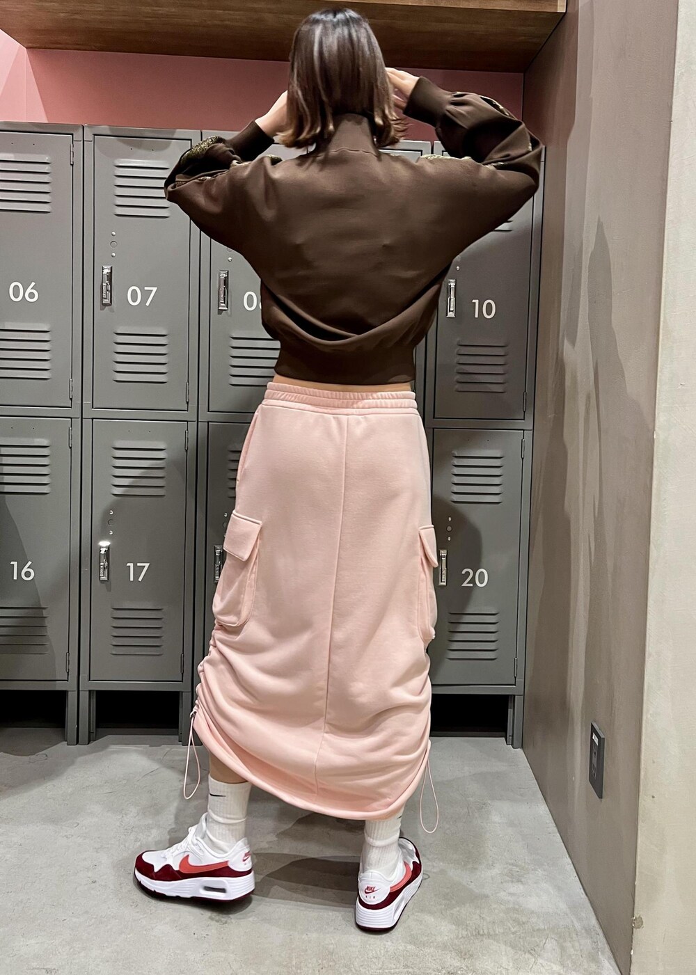 ピンク系のスカート、ブラウン系のその他アウター、ホワイト系のスニーカーを着用したレディースの冬コーディネートの3枚目の写真