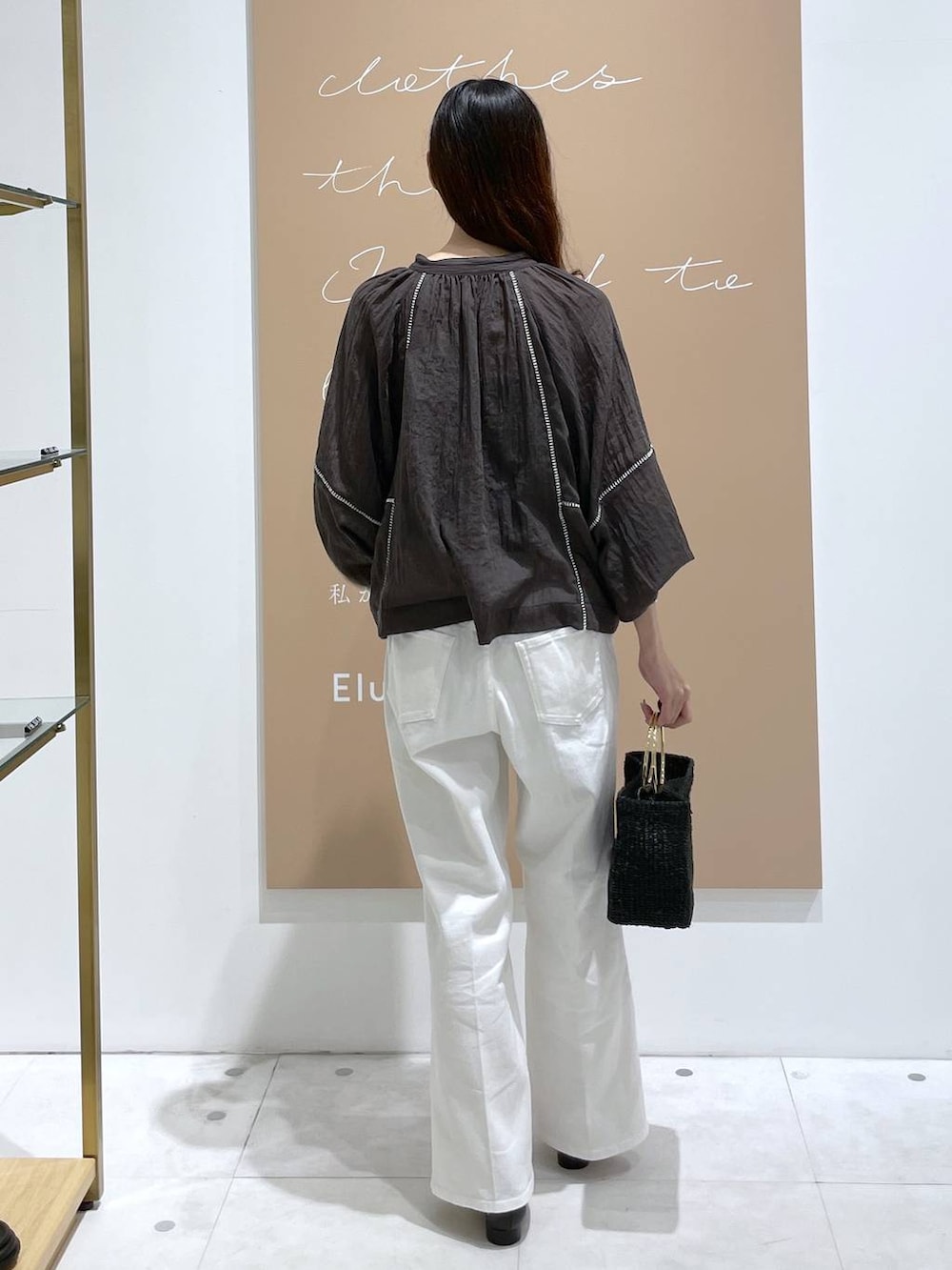ブラック系のサンダル、ブラック系のトートバッグ、ホワイト系のデニムパンツを着用したレディースの秋コーディネートの3枚目の写真