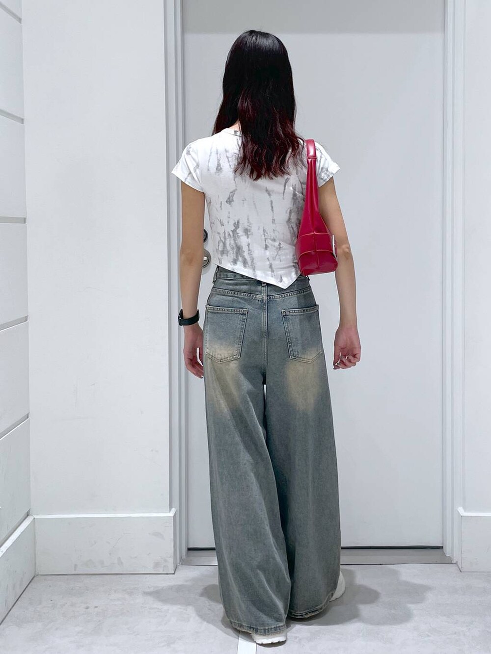 ブルー系のデニムパンツ、レッド系のショルダーバッグ、ホワイト系のTシャツ/カットソーを着用したレディースの夏コーディネートの3枚目の写真