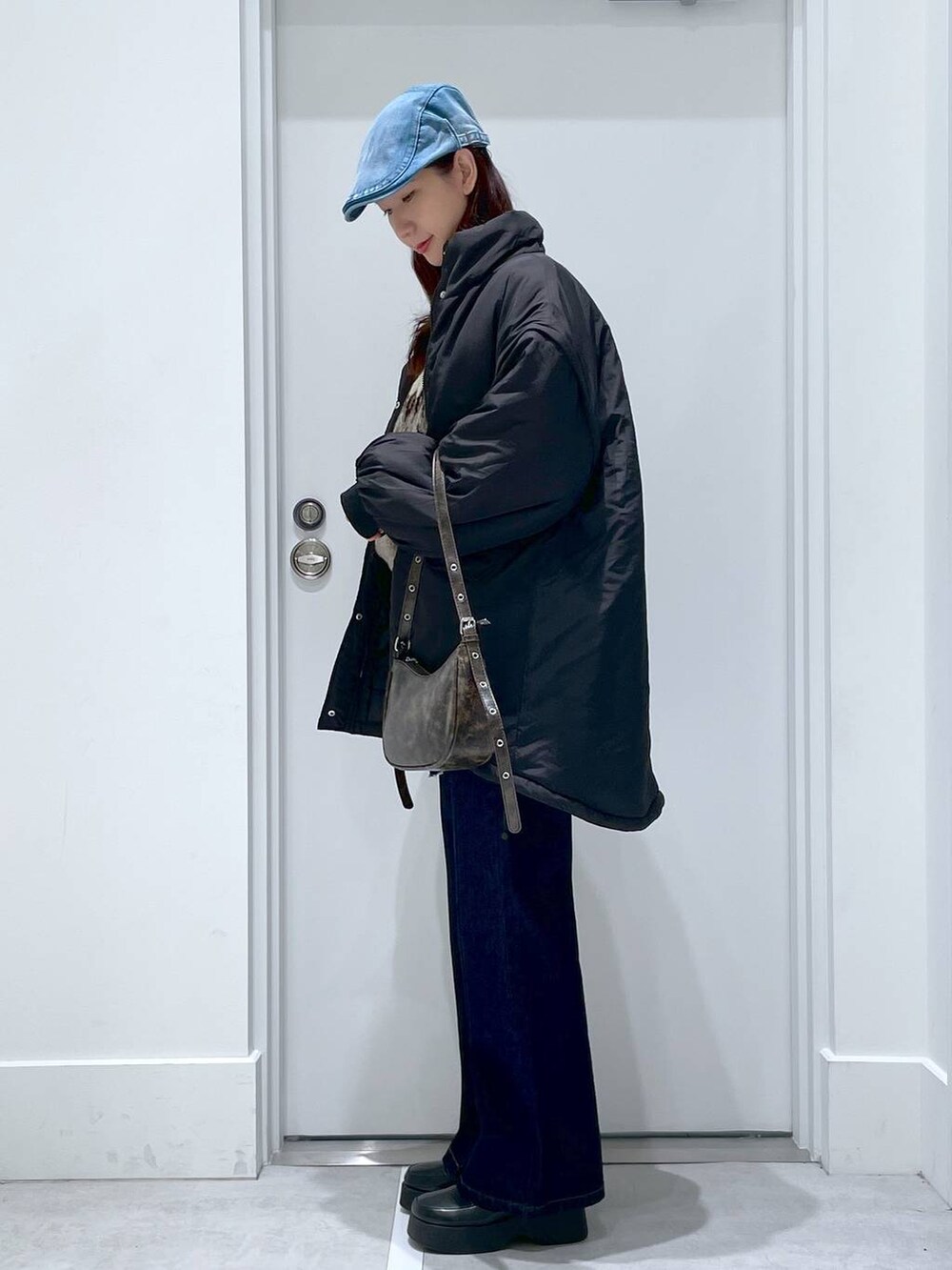 ブラック系のブルゾン、ホワイト系のスリッポン、ブルー系のデニムパンツを着用したレディースの冬コーディネートの2枚目の写真