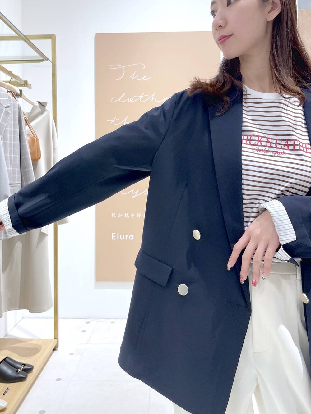 グレー系のパーカー、ブラック系のハンドバッグ、ブルー系のテーラードジャケットを着用したレディースの春コーディネートの4枚目の写真