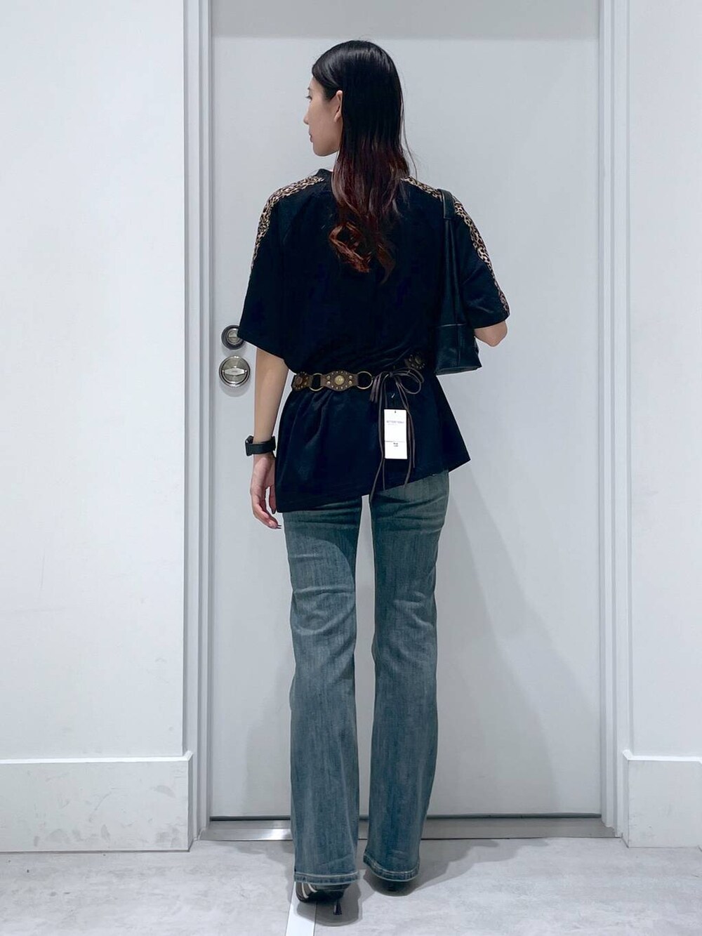 ブルー系のデニムパンツ、ブラック系のパンプス、ブラック系のショルダーバッグを着用したレディースの夏コーディネートの3枚目の写真