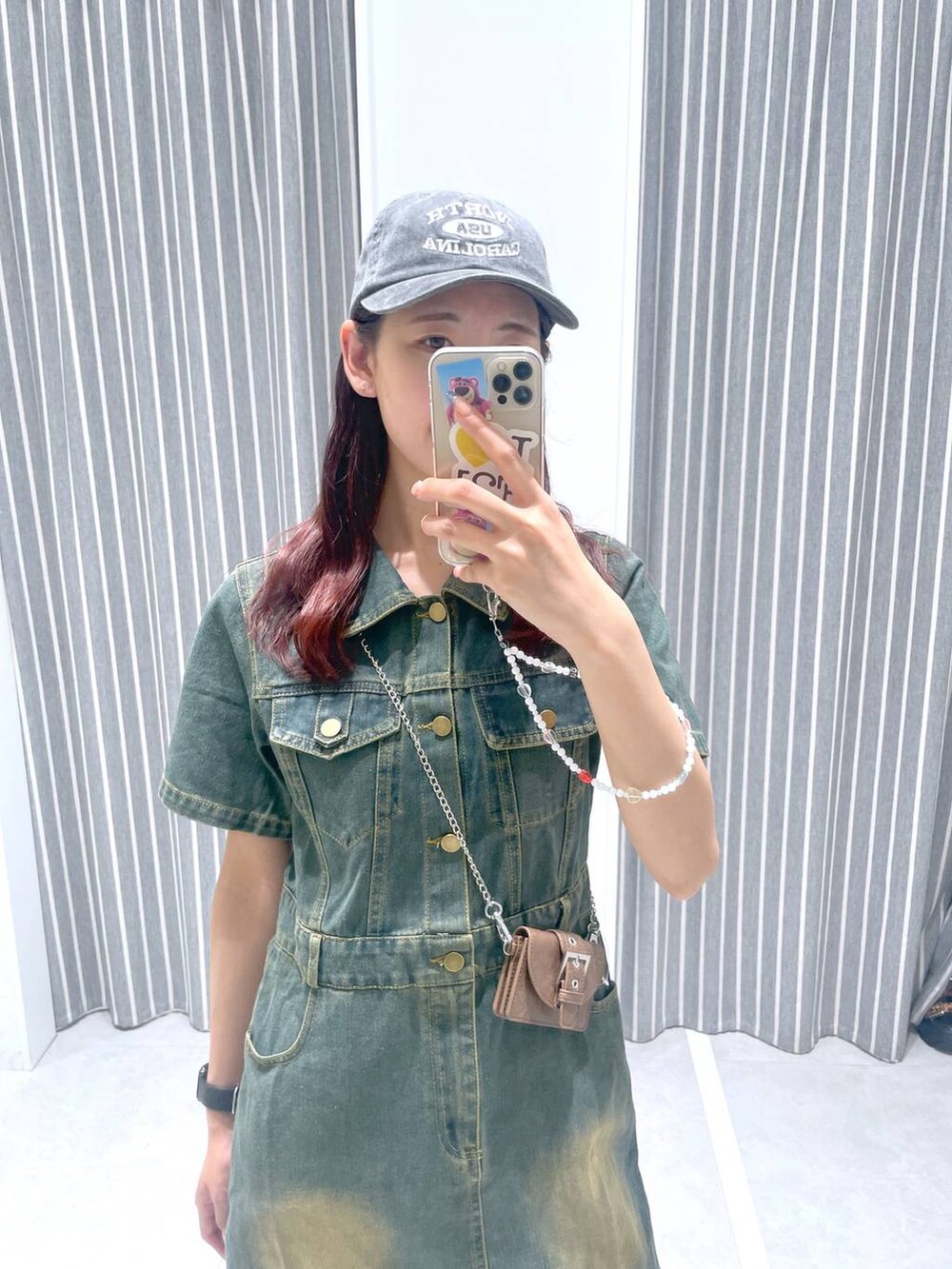 ブルー系のワンピース、ブラウン系のキャップ、ホワイト系のスマホケース/カバーを着用したレディースの夏コーディネートの2枚目の写真