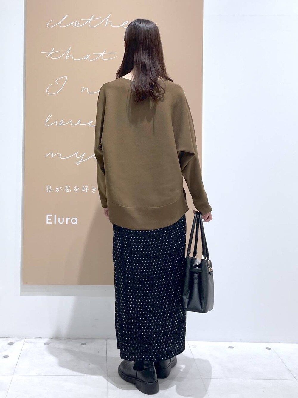 ブラック系のスカート、ブラック系のハンドバッグ、ブラウン系のニット/セーターを着用したレディースの春コーディネートの3枚目の写真