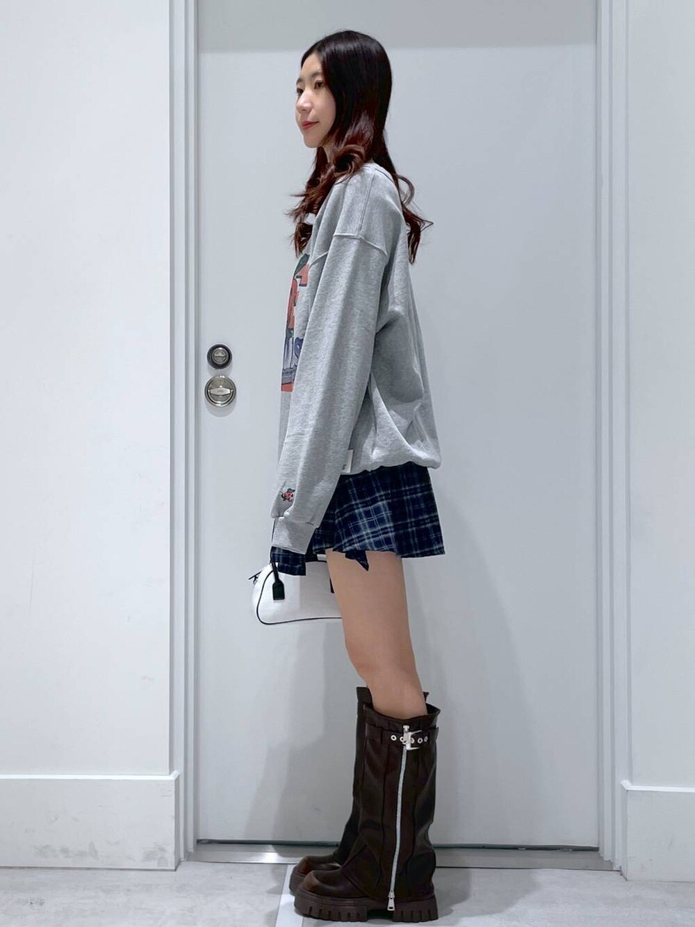 ホワイト系のハンドバッグ、ブラウン系のブーツ、ブルー系のその他パンツを着用したレディースの冬コーディネートの2枚目の写真