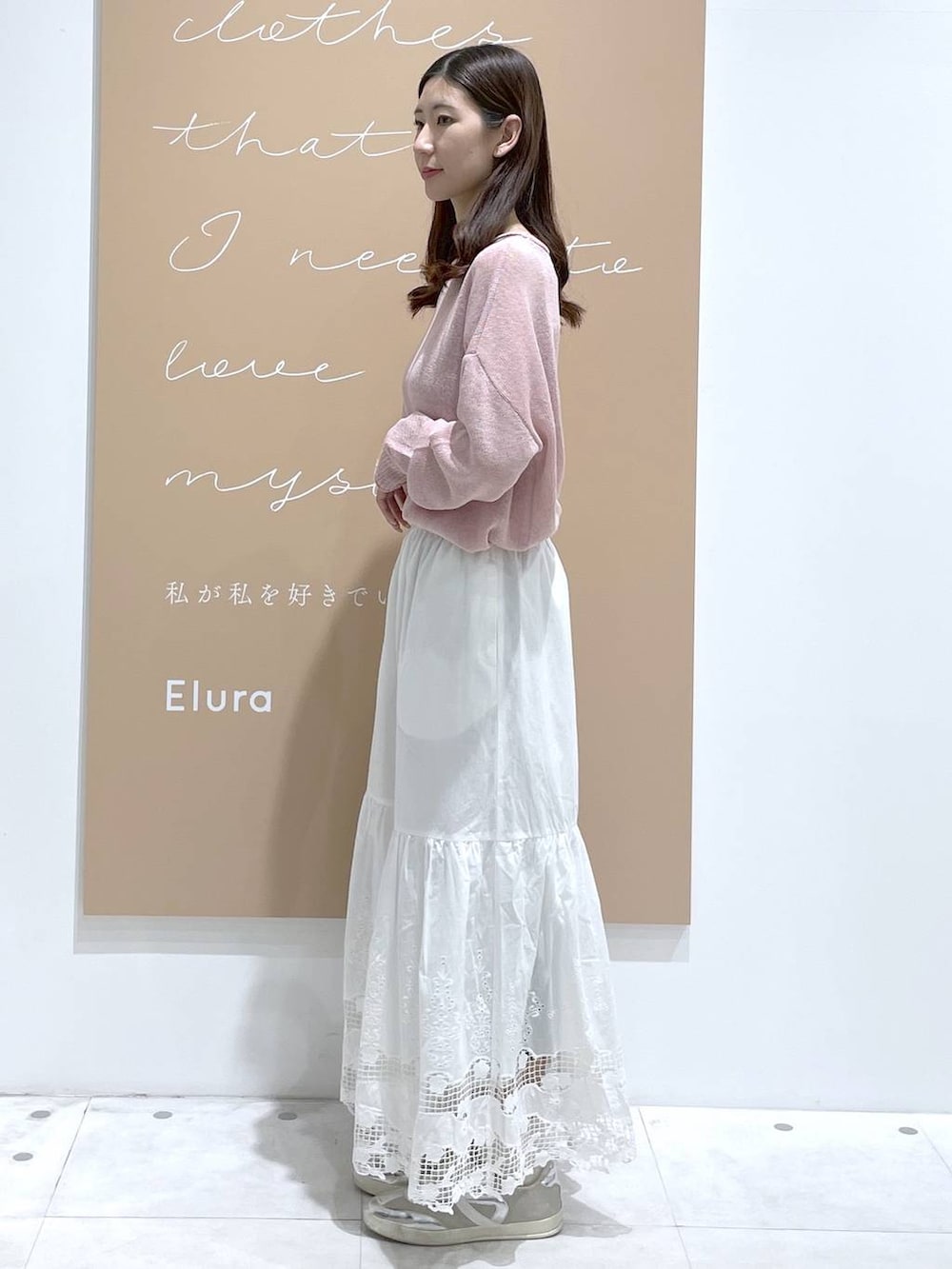 イエロー系のハンドバッグ、ピンク系のニット/セーター、ホワイト系のスカートを着用したレディースの春コーディネートの2枚目の写真