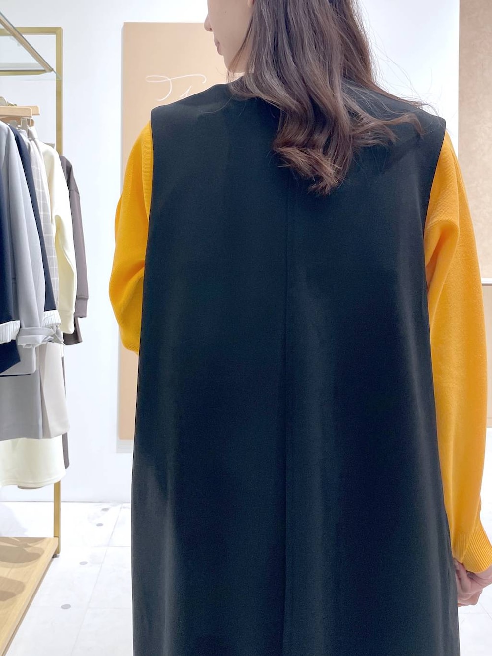 ベージュ系のトートバッグ、ホワイト系のタンクトップ、ブラック系のジャンパースカートを着用したレディースの春コーディネートの6枚目の写真