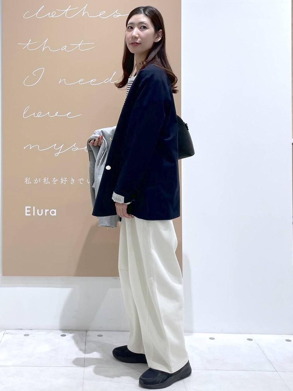 グレー系のパーカー、ブラック系のハンドバッグ、ブルー系のテーラードジャケットを着用したレディースの春コーディネートの2枚目の写真