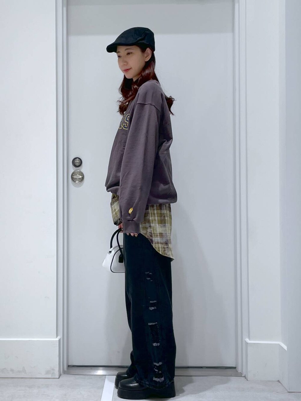 ホワイト系のハンドバッグ、ブラック系のスリッポン、ブラック系のデニムパンツを着用したレディースの冬コーディネートの2枚目の写真