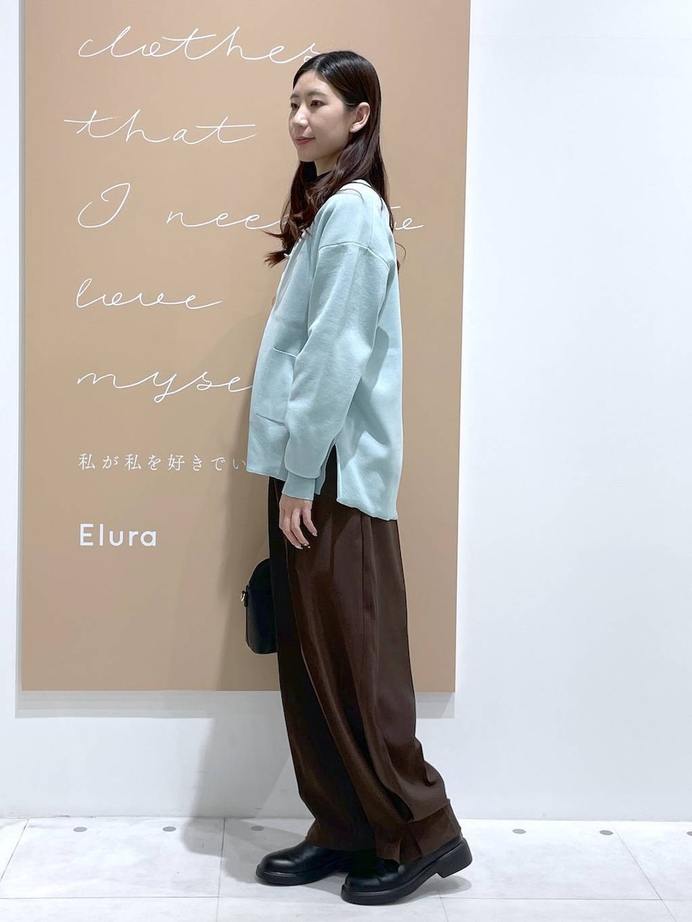 ブラック系のTシャツ/カットソー、グリーン系のカーディガン/ボレロ、ブラック系のハンドバッグを着用したレディースの冬コーディネートの2枚目の写真