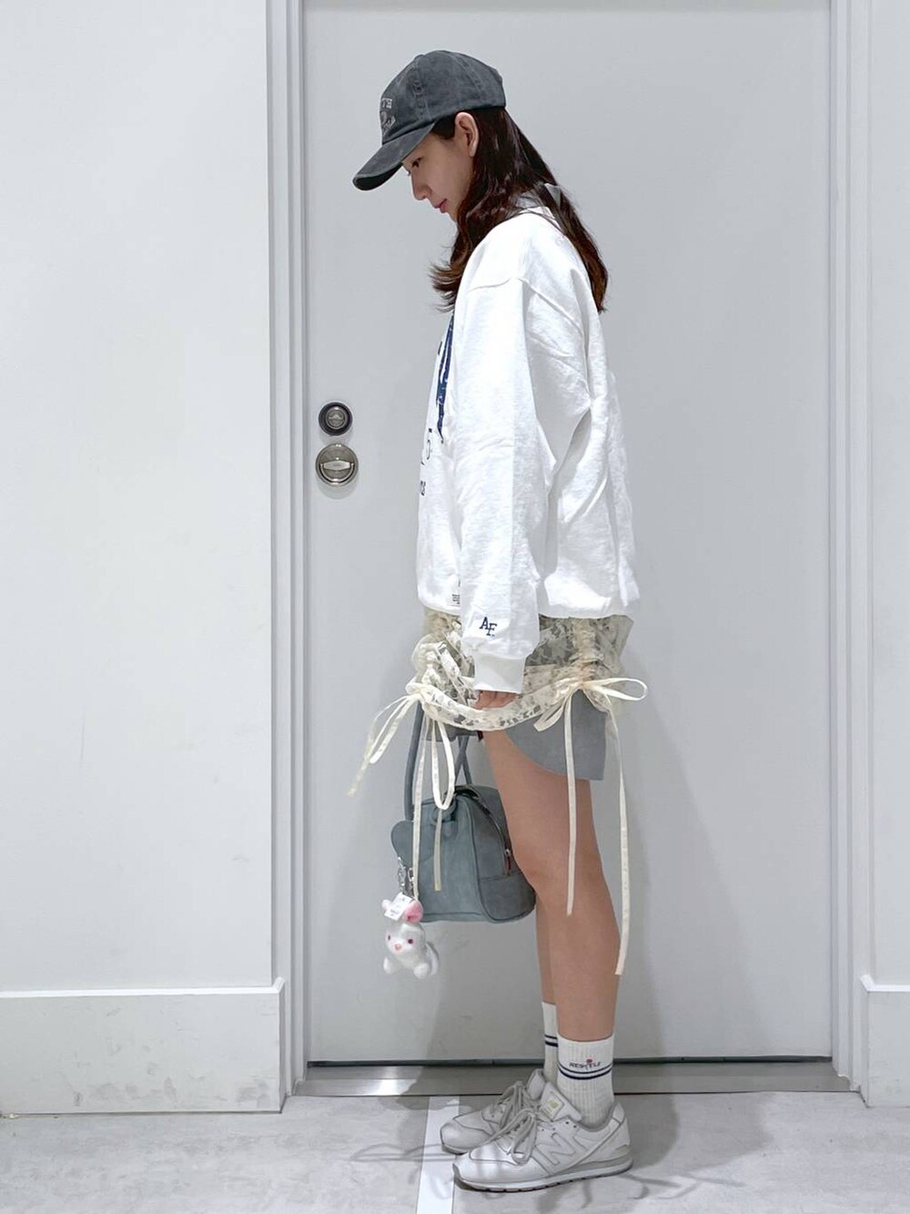 ベージュ系のワンピース、ホワイト系のスウェット、ブルー系のショルダーバッグを着用したレディースの春コーディネートの2枚目の写真