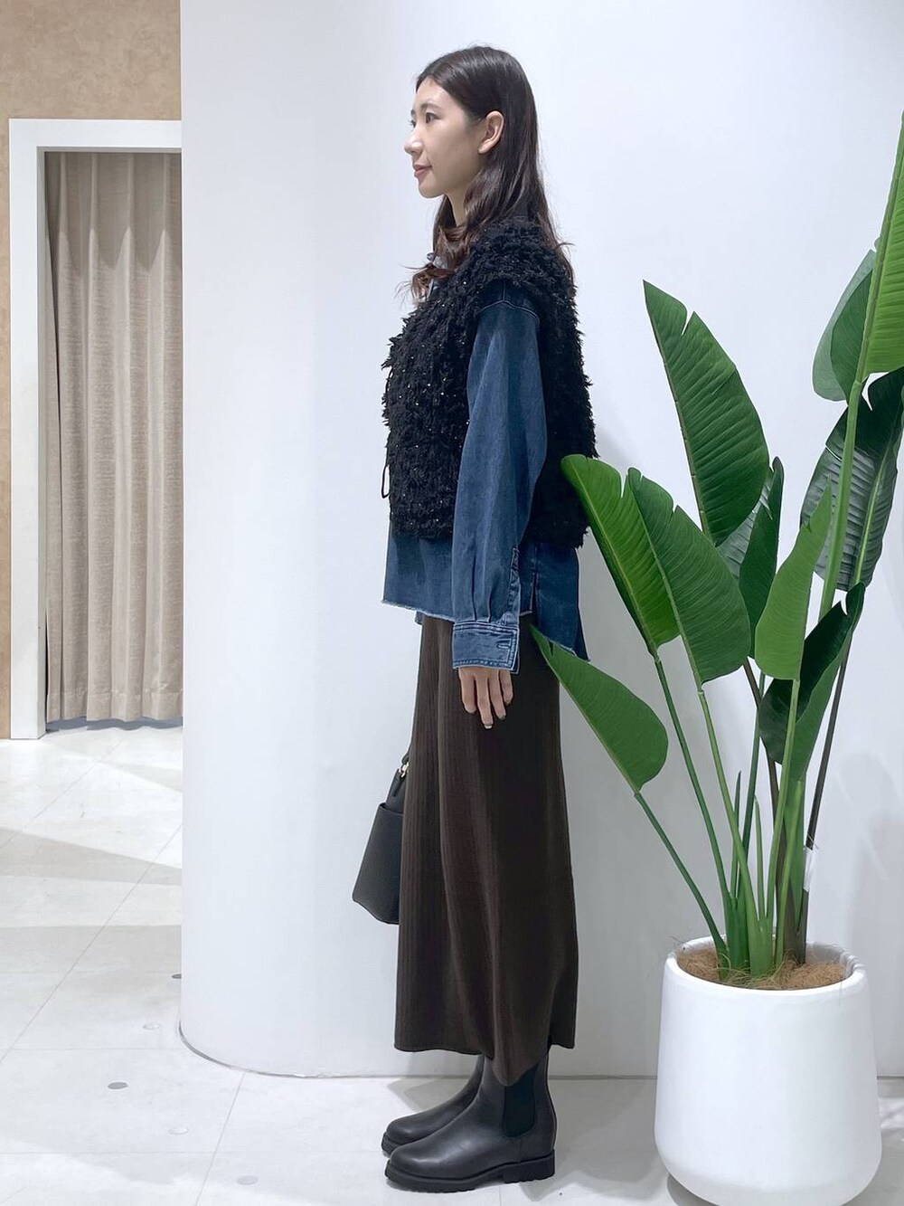 ブラウン系のスカート、ブラック系のブーツ、ブラック系のショルダーバッグを着用したレディースの秋コーディネートの2枚目の写真