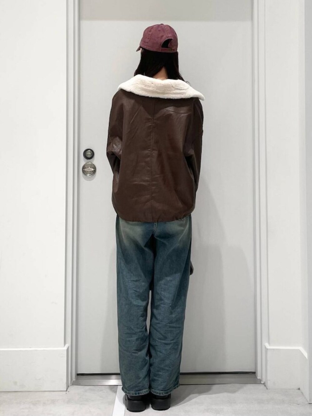 ブルー系のデニムパンツ、グレー系のニット/セーター、ブラウン系のブルゾンを着用したレディースの秋コーディネートの3枚目の写真