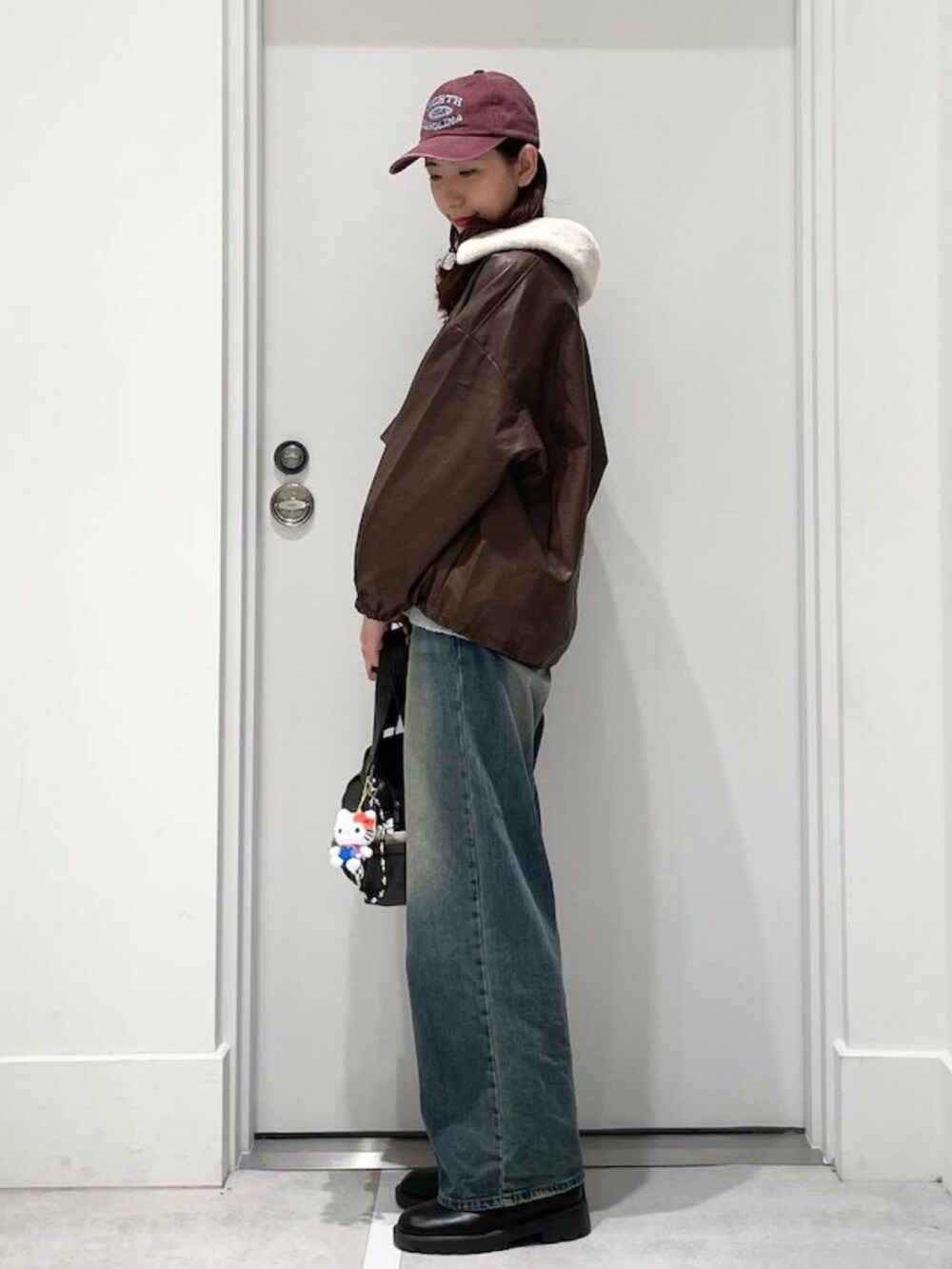 ブルー系のデニムパンツ、グレー系のニット/セーター、ブラウン系のブルゾンを着用したレディースの秋コーディネートの2枚目の写真