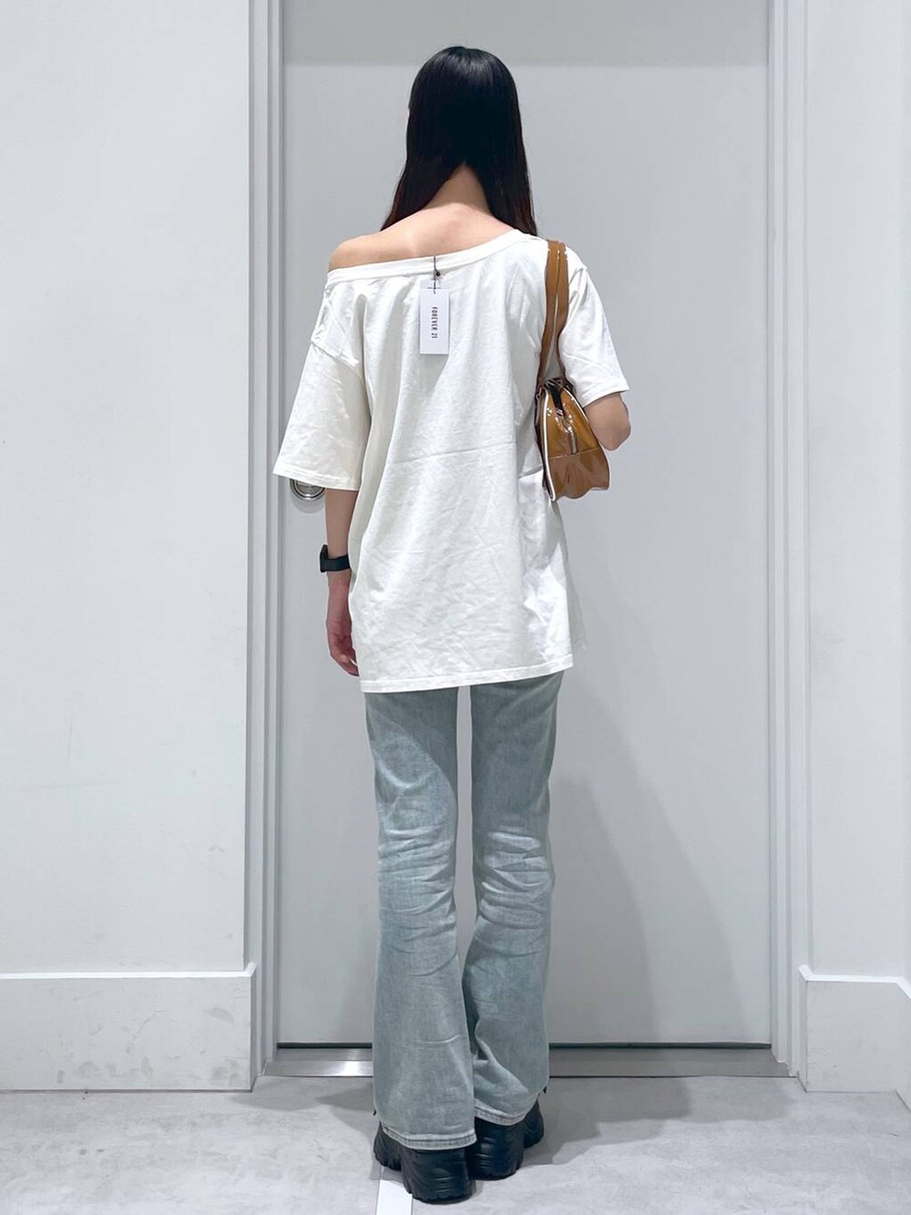 ブルー系のデニムパンツ、ブラック系のサンダル、ブラウン系のボストンバッグを着用したレディースの夏コーディネートの3枚目の写真