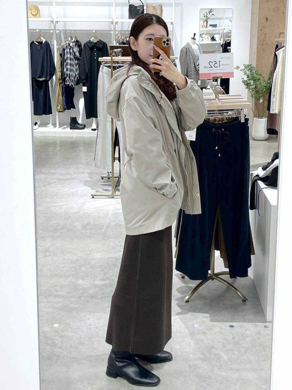 ブラウン系のTシャツ/カットソー、ブラウン系のスカート、ベージュ系のマウンテンパーカーを着用したレディースの秋コーディネートの2枚目の写真